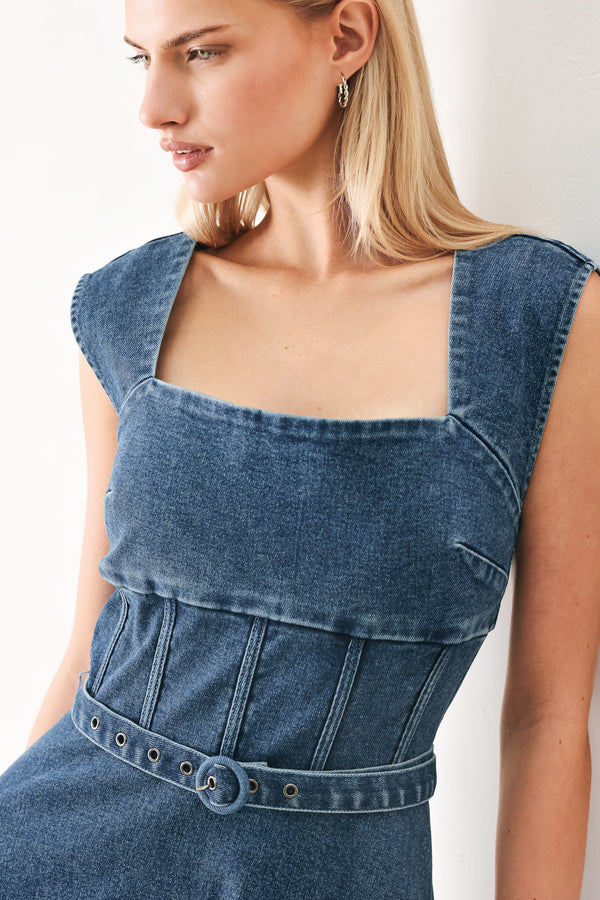 Woman wearing a blue denim midi dress featuring square neckline, corset waist, self belt, side pockets and back zipper closure | FREEMARKET