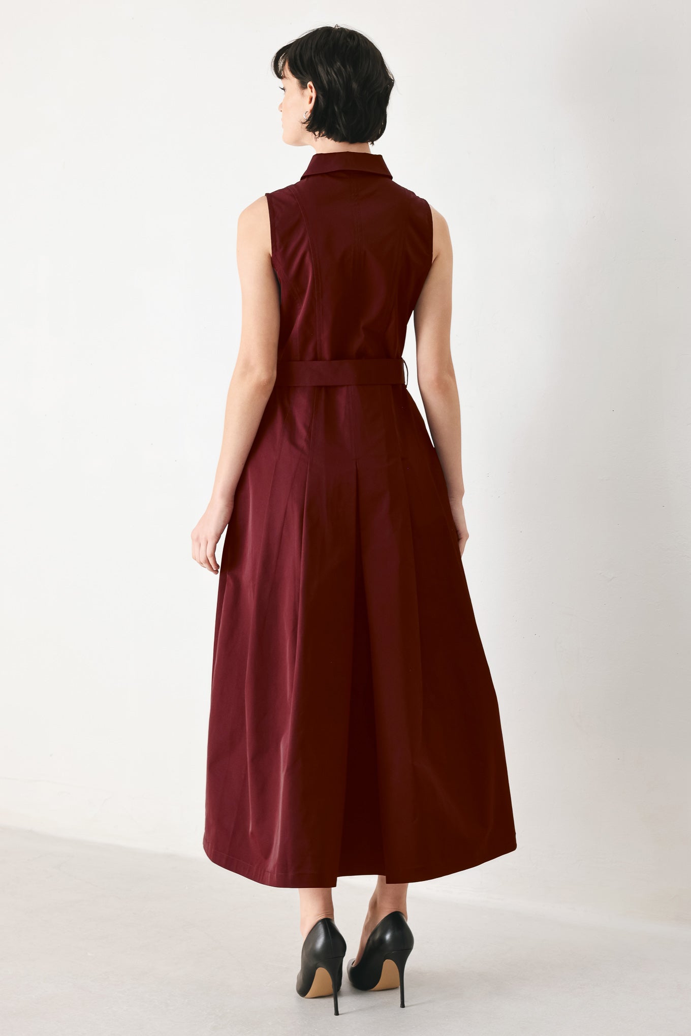 Woman wearing a burgundy red woven midi dress featuring collar, sleeveless, front zipper closure, self sash tie, pockets and full skirt | FREEMARKET