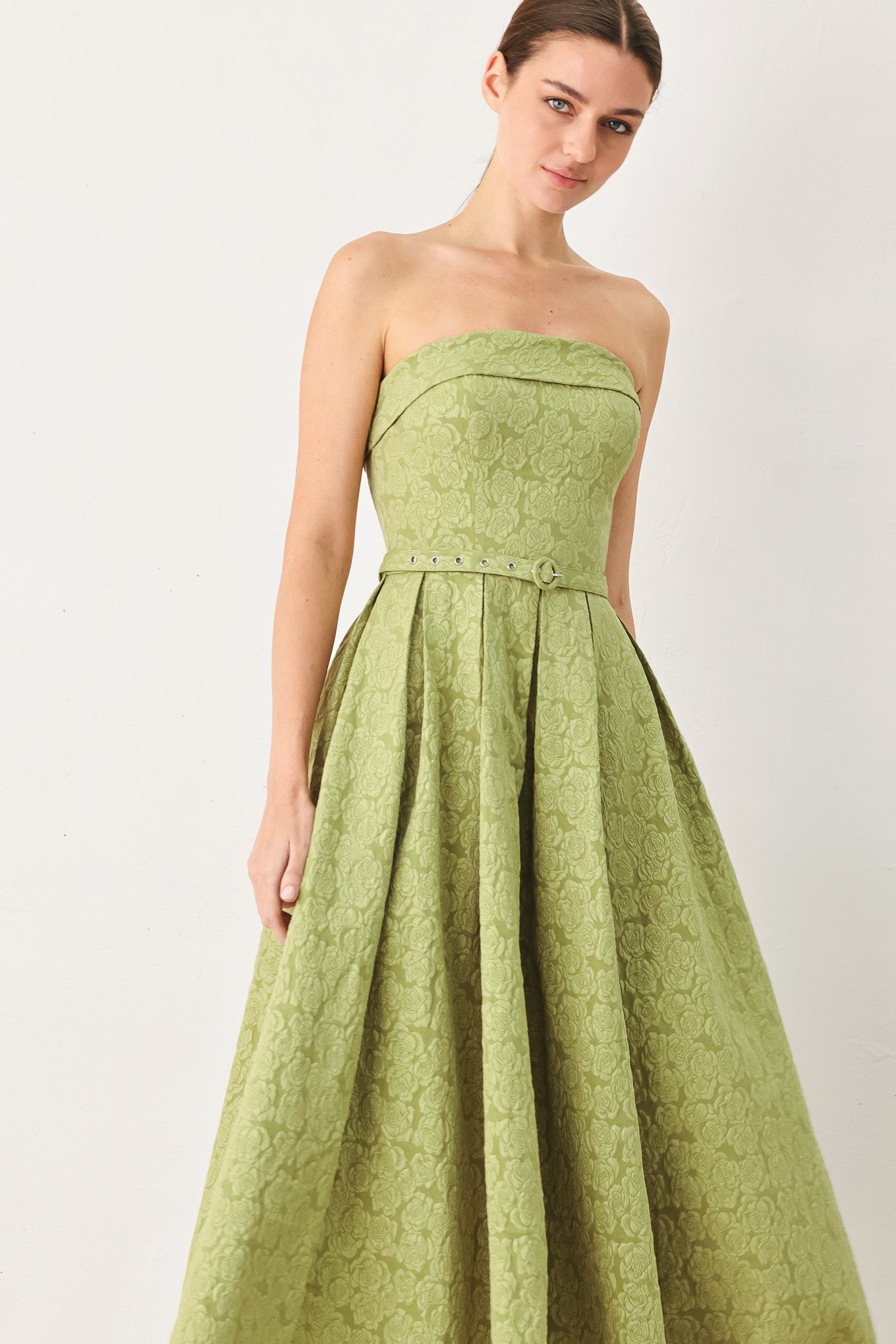 A woman modeling a strapless midi dress in a light olive green color with a textured jacquard pattern | FREEMARKET