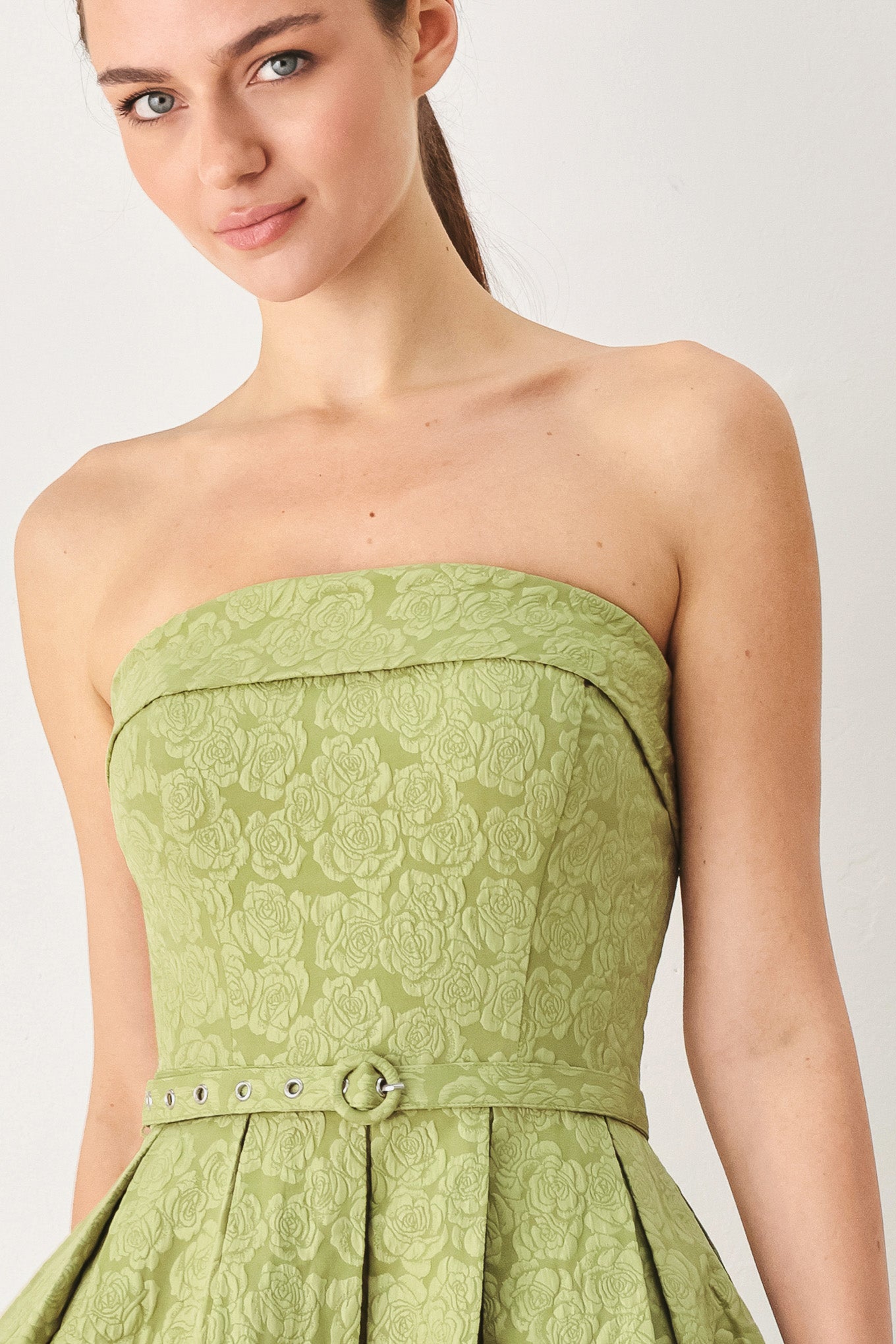 A woman modeling a strapless midi dress in a light olive color with a textured jacquard pattern | FREEMARKET
