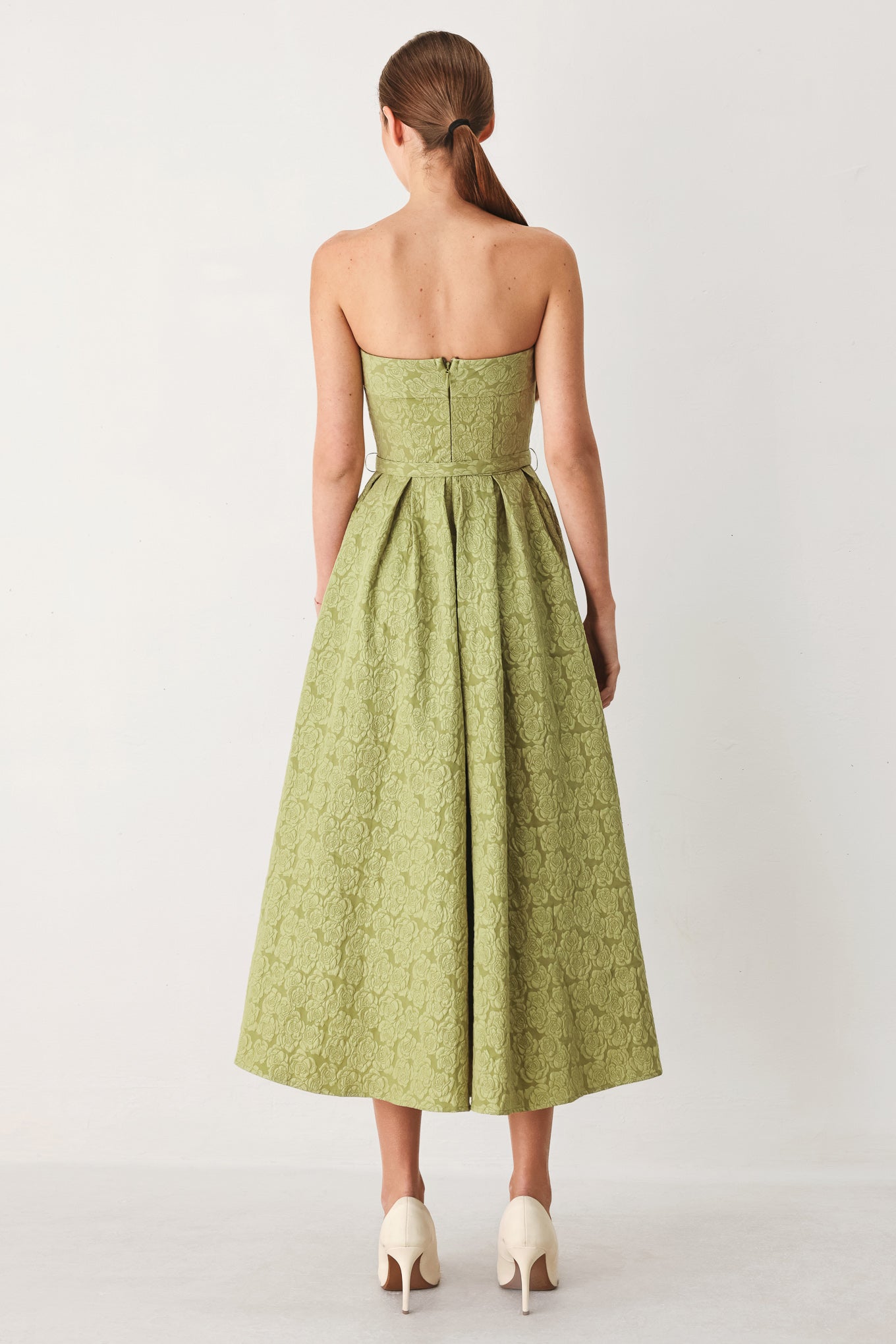 A woman modeling a strapless midi dress in a light olive color with a textured jacquard pattern | FREEMARKET