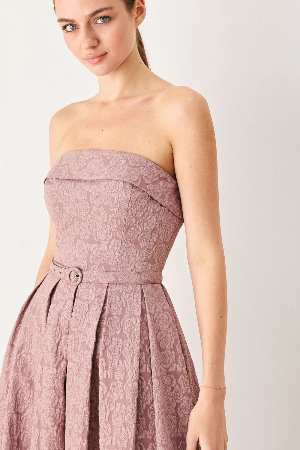 A woman modeling a strapless midi dress in a dusty rose pink color with a textured jacquard pattern | FREEMARKET