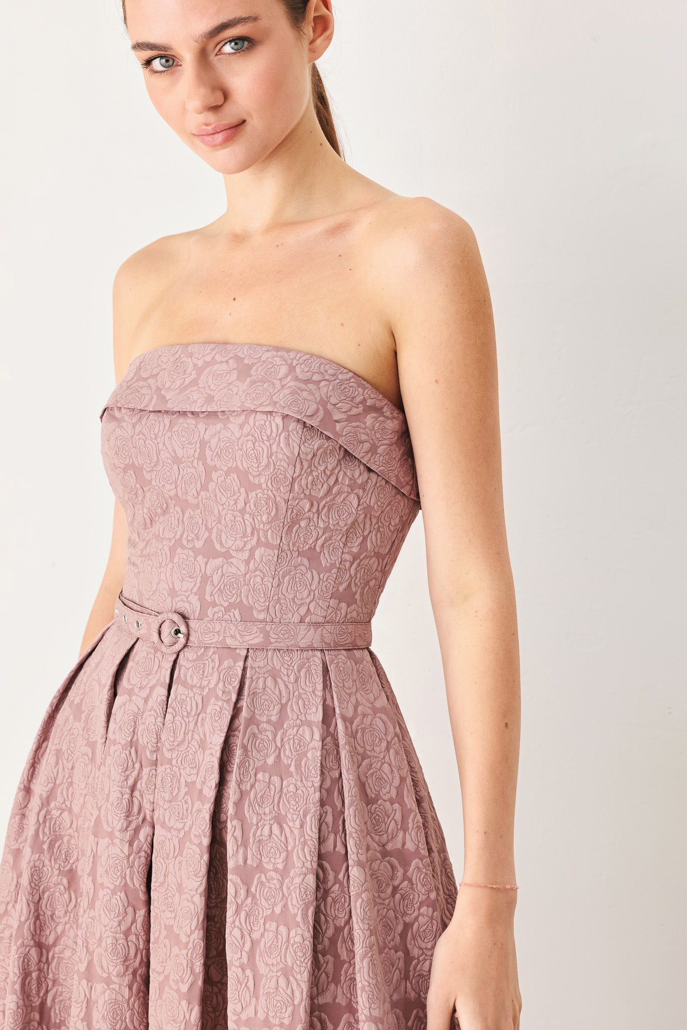 A woman modeling a strapless midi dress in a dusty rose pink color with a textured jacquard pattern | FREEMARKET