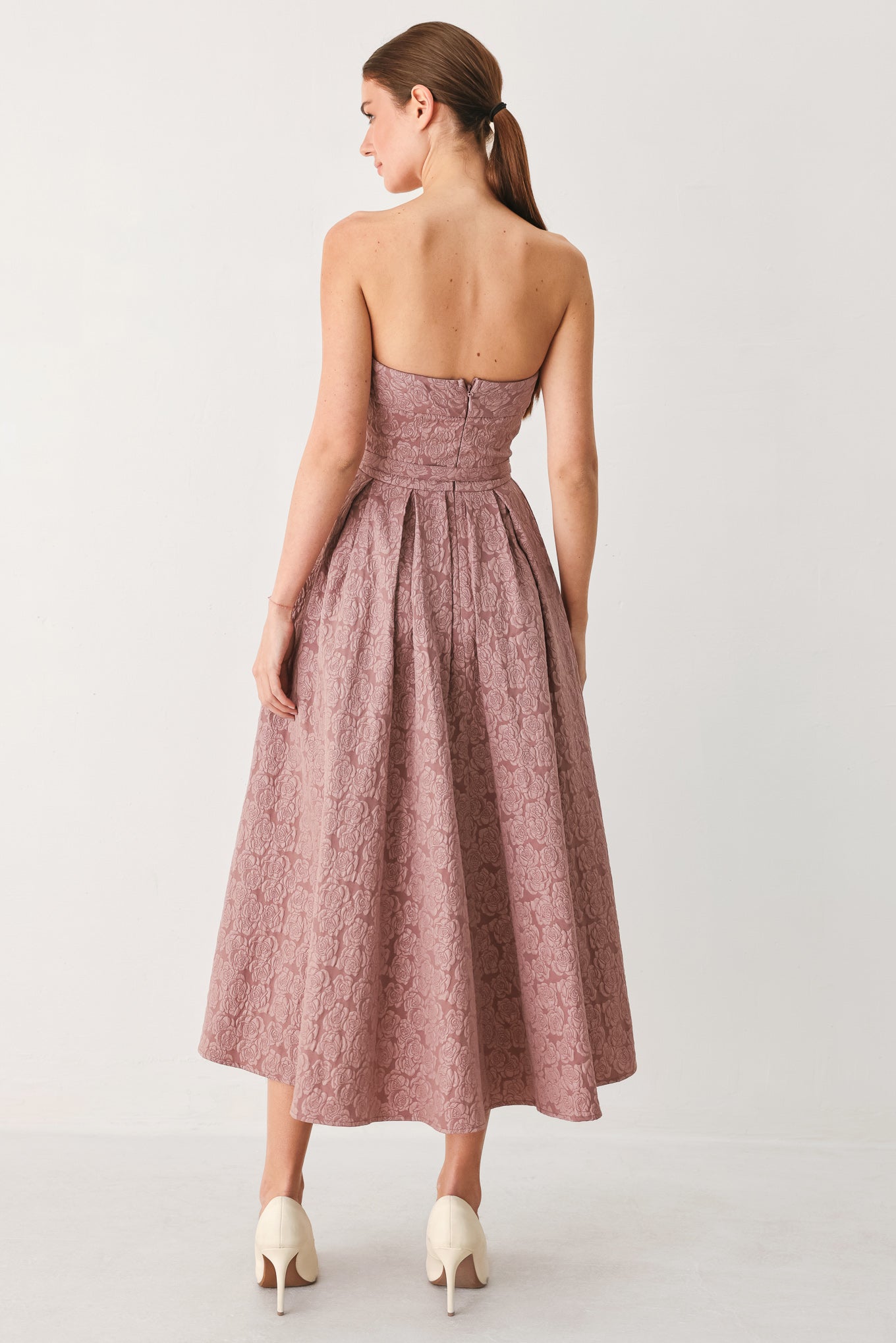A woman modeling a strapless midi dress in a dusty rose pink color with a textured jacquard pattern | FREEMARKET