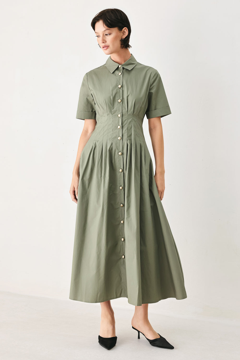 Woman wearing an olive midi dress featuring collar, short sleeve, button down, corset waist, side pockets and full skirt | FREEMARKET