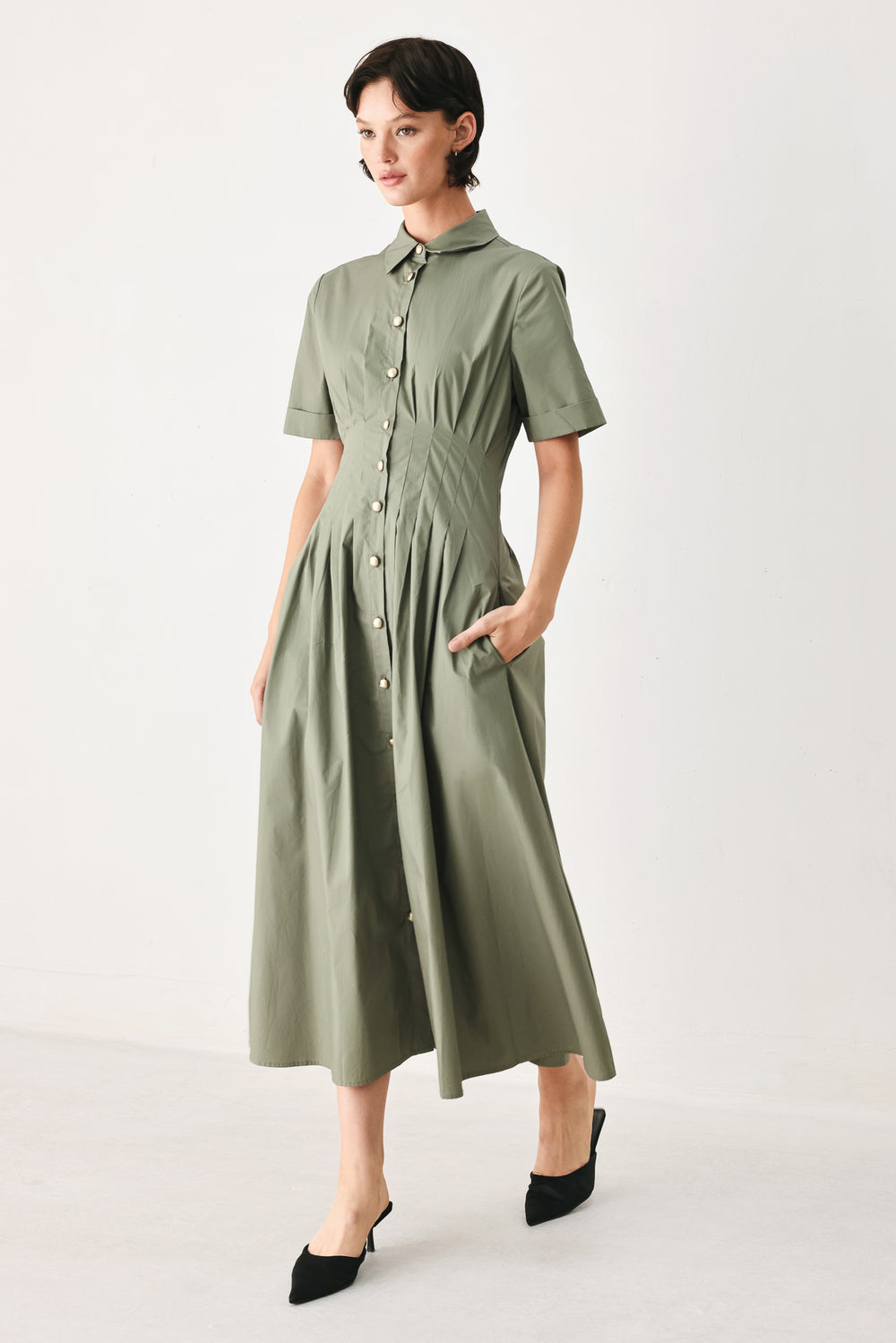 Woman wearing an olive midi dress featuring collar, short sleeve, button down, corset waist, side pockets and full skirt | FREEMARKET