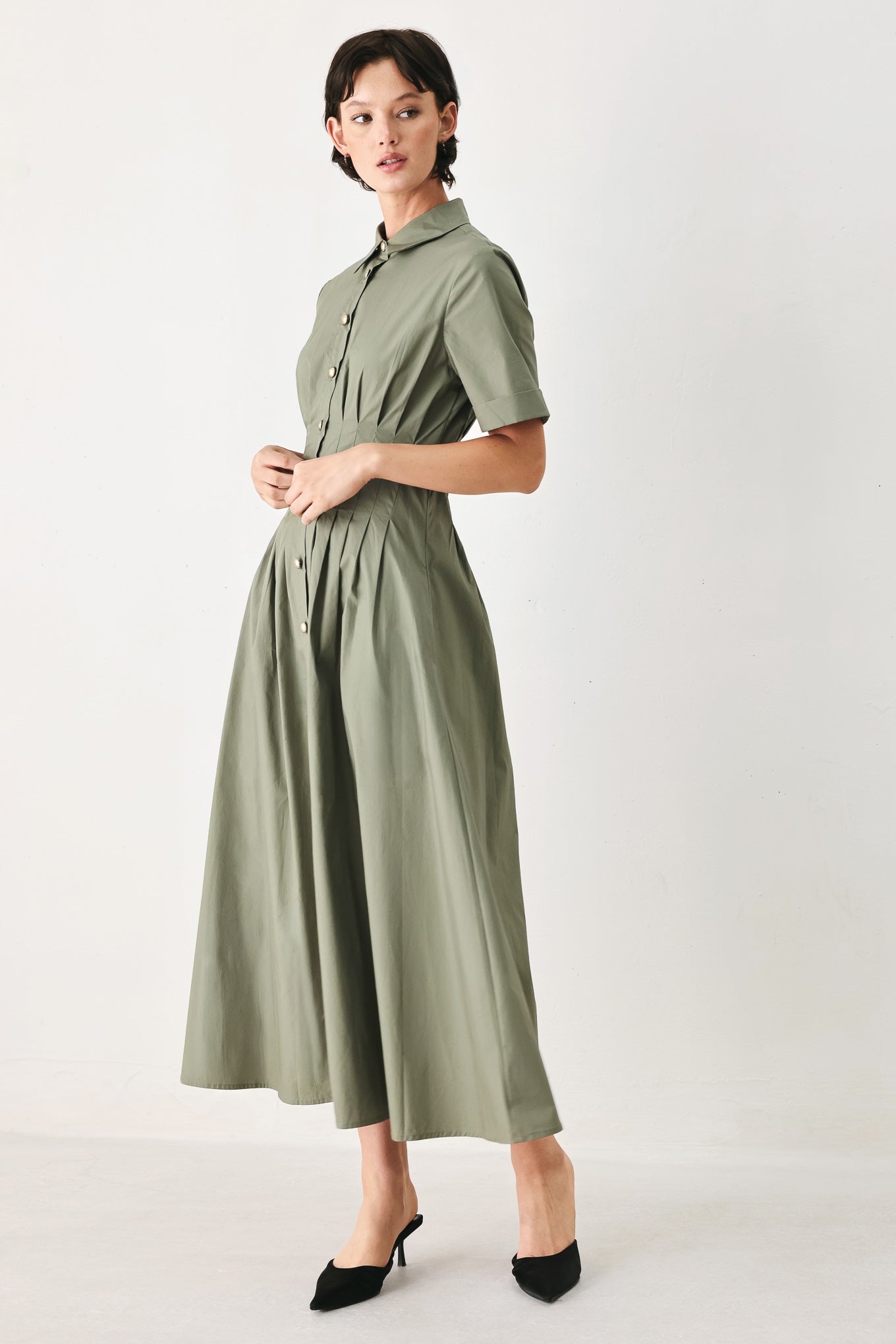 Woman wearing an olive midi dress featuring collar, short sleeve, button down, corset waist, side pockets and full skirt | FREEMARKET