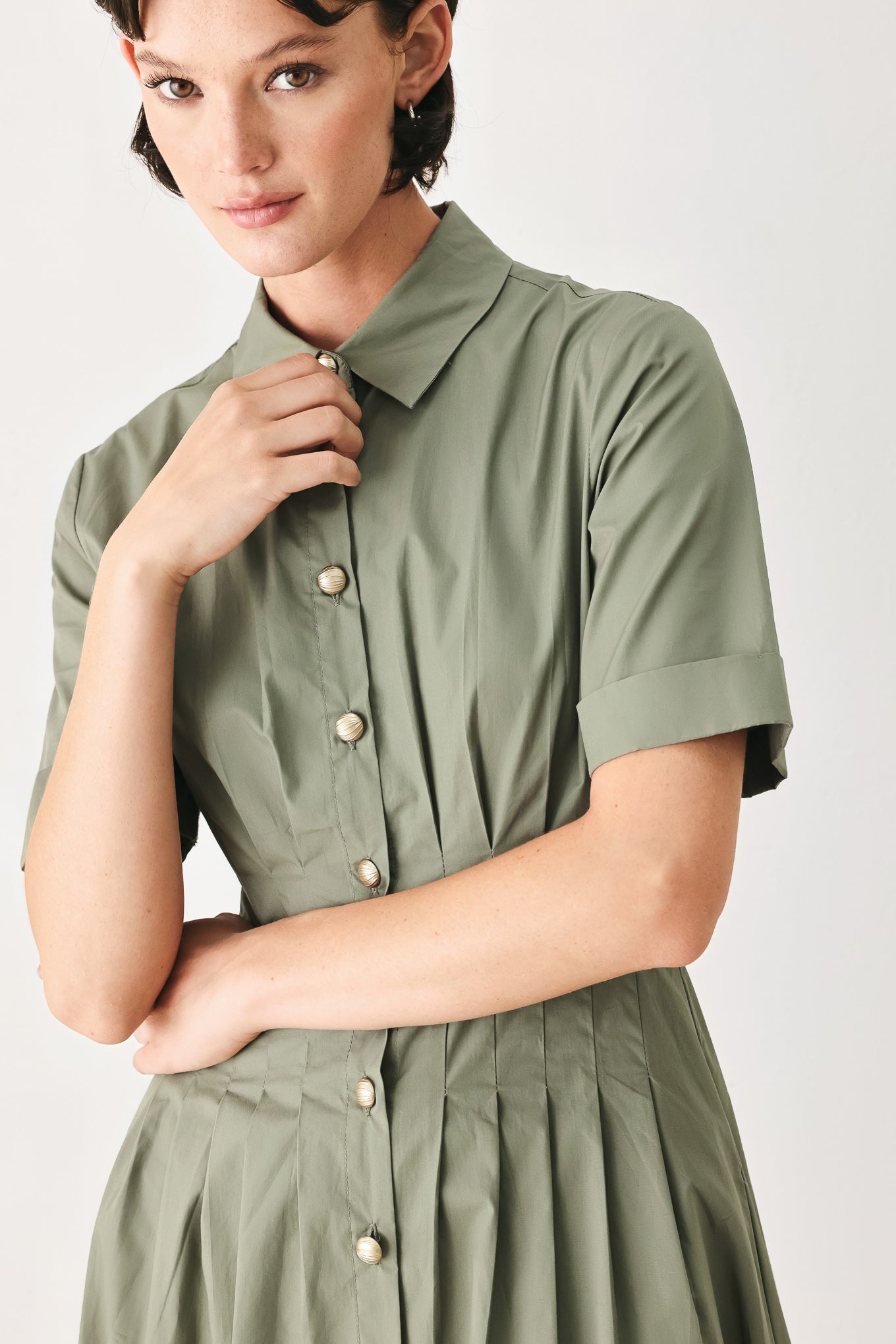 Woman wearing an olive midi dress featuring collar, short sleeve, button down, corset waist, side pockets and full skirt | FREEMARKET