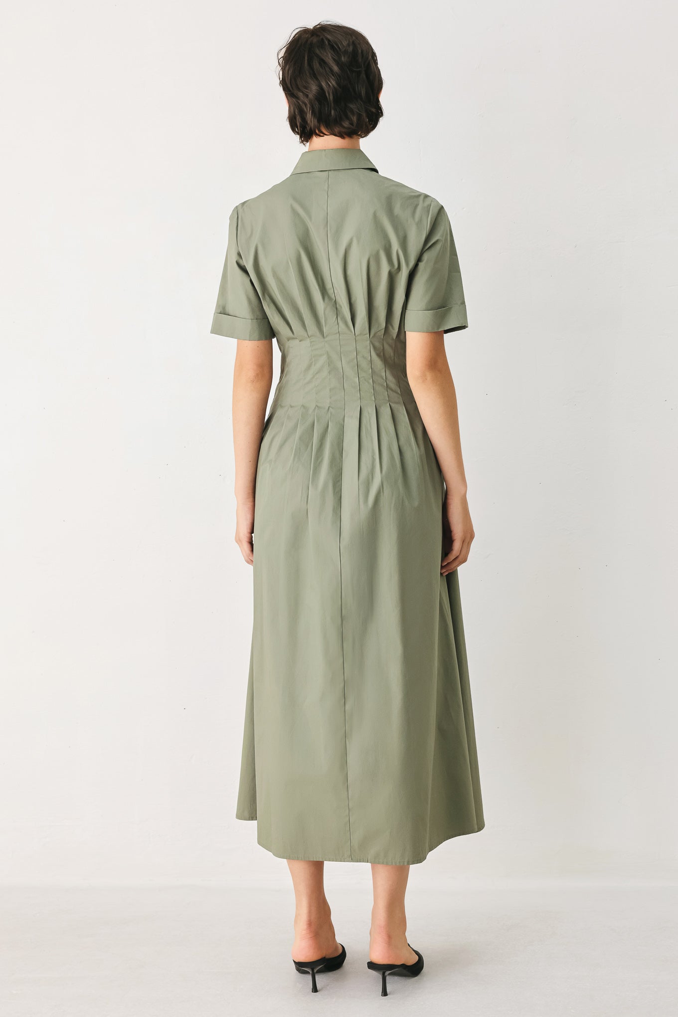 Woman wearing an olive midi dress featuring collar, short sleeve, button down, corset waist, side pockets and full skirt | FREEMARKET