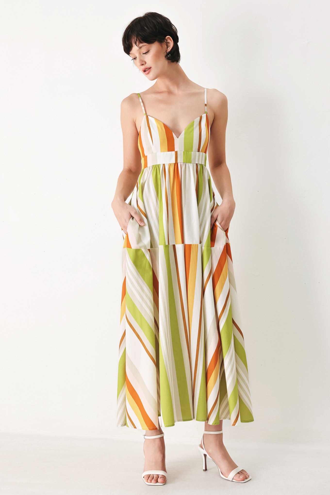 Woman wearing a colorful white, green, orange, and yellow striped midi dress featuring cami top, straps, full skirt and back zipper closure | FREEMARKET