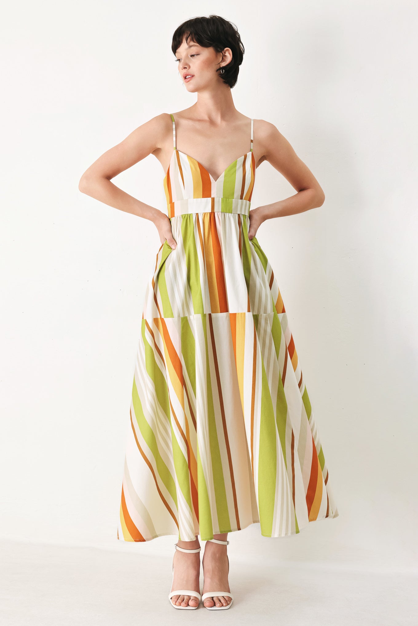 Woman wearing a colorful white, green, orange, and yellow striped midi dress featuring cami top, straps, full skirt and back zipper closure | FREEMARKET