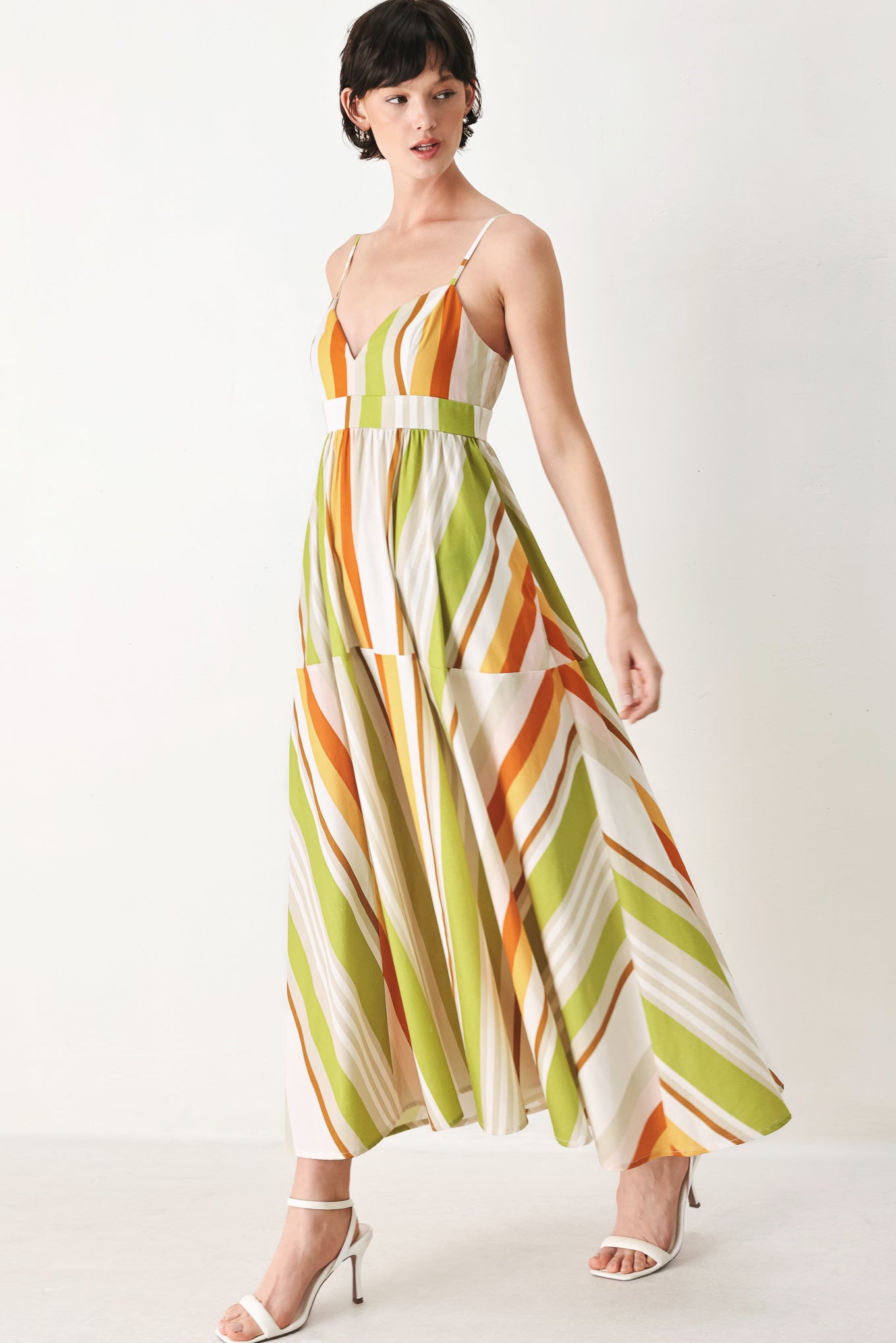 Woman wearing a colorful white, green, orange, and yellow striped midi dress featuring cami top, straps, full skirt and back zipper closure | FREEMARKET