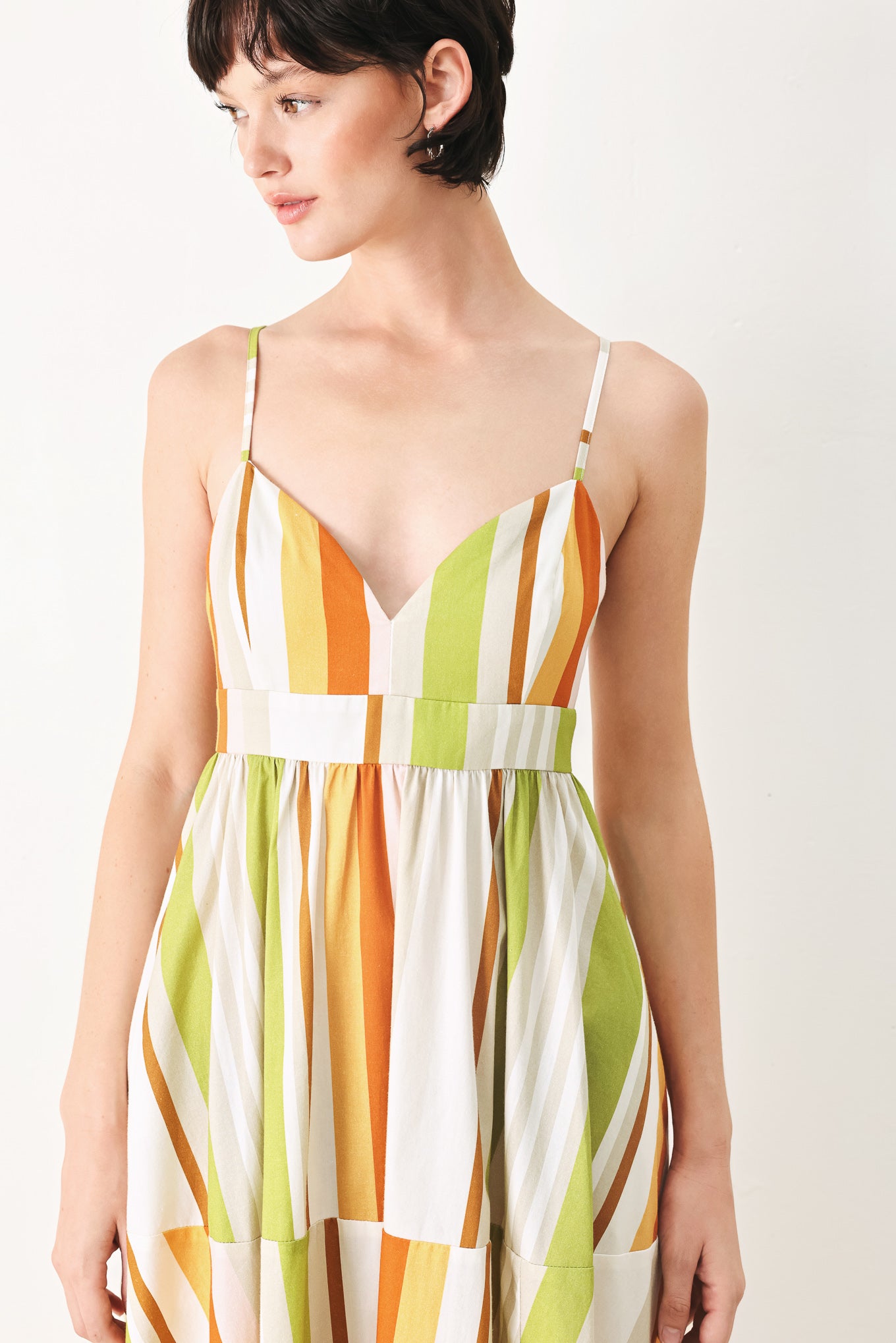 Woman wearing a colorful white, green, orange, and yellow striped midi dress featuring cami top, straps, full skirt and back zipper closure | FREEMARKET