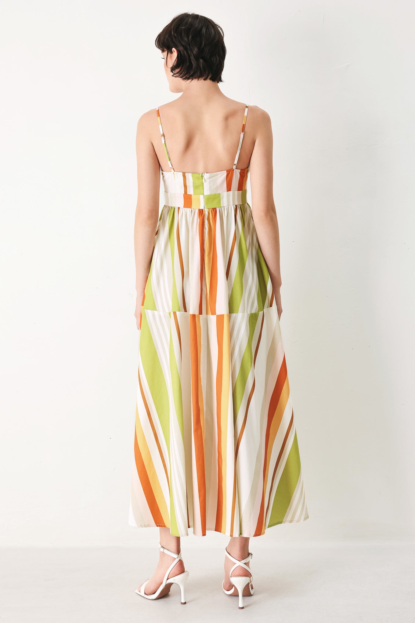 Woman wearing a colorful white, green, orange, and yellow striped midi dress featuring cami top, straps, full skirt and back zipper closure | FREEMARKET