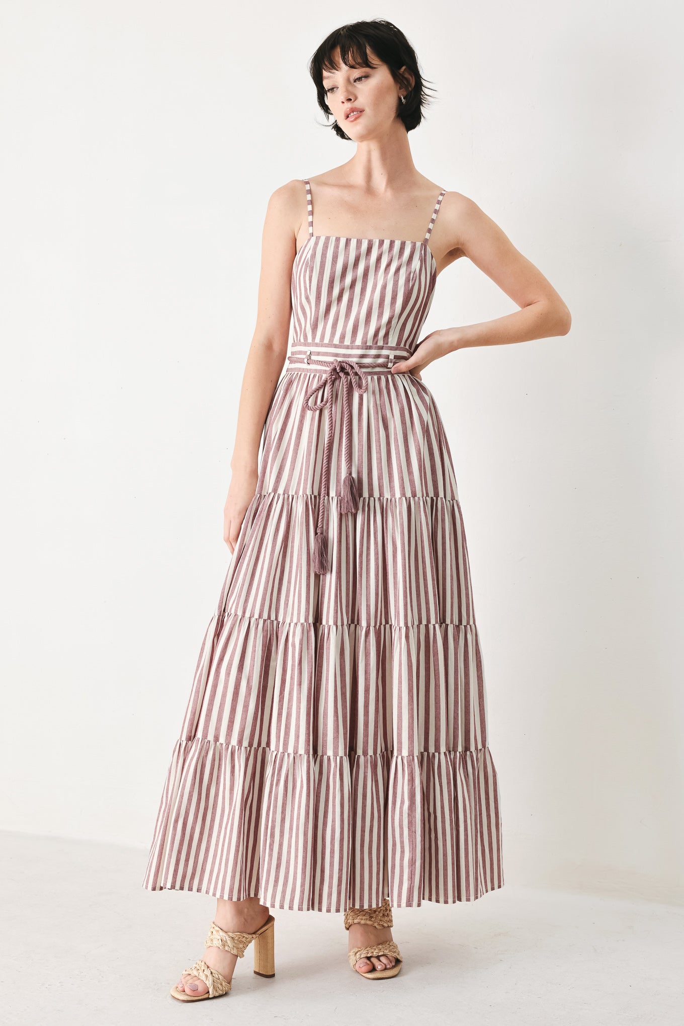 Woman wearing a burgundy striped woven ankle dress featuring straight neckline, straps, rope tie, tier skirt and back zipper closure | FREEMARKET