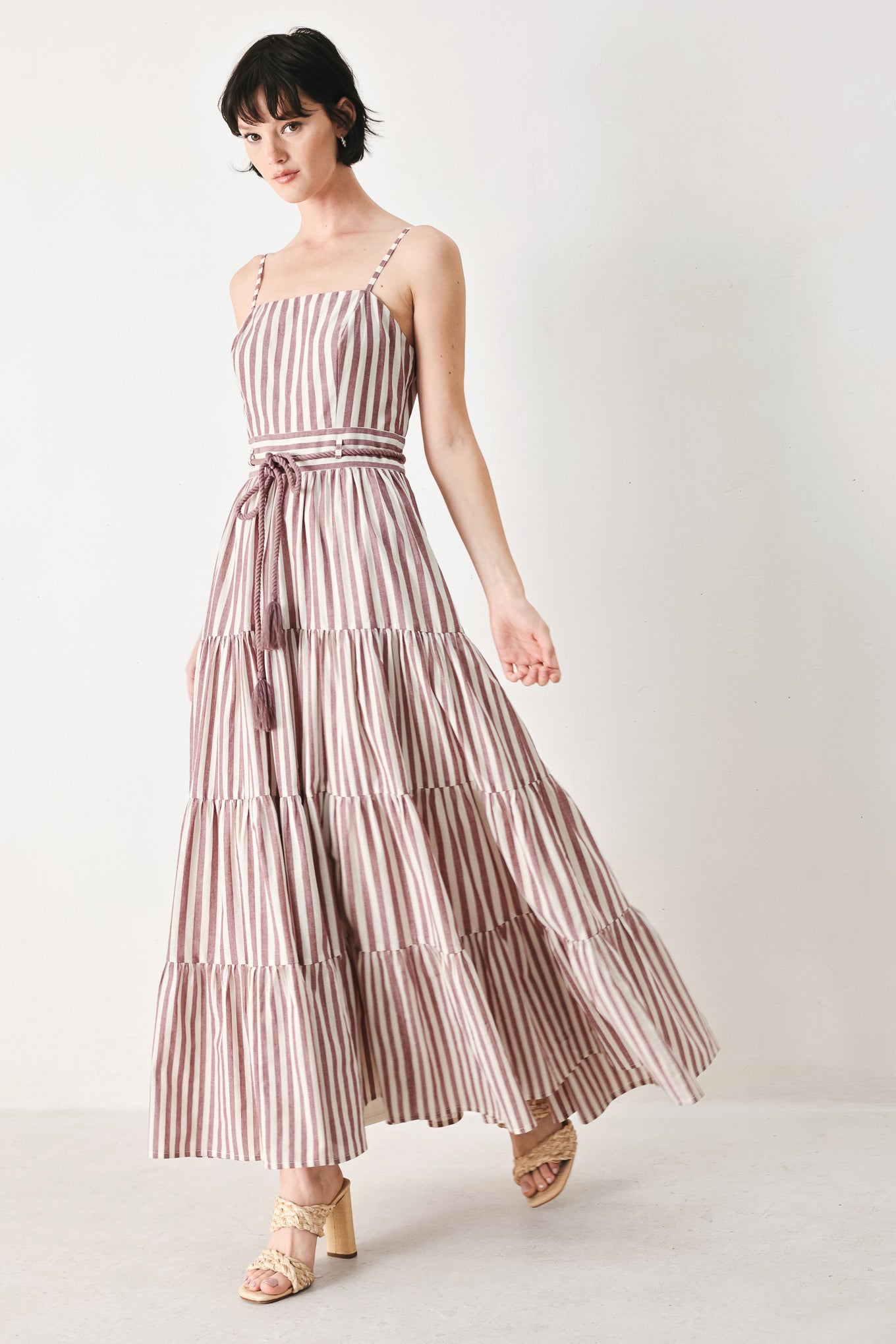 Woman wearing a burgundy striped woven ankle dress featuring straight neckline, straps, rope tie, tier skirt and back zipper closure | FREEMARKET