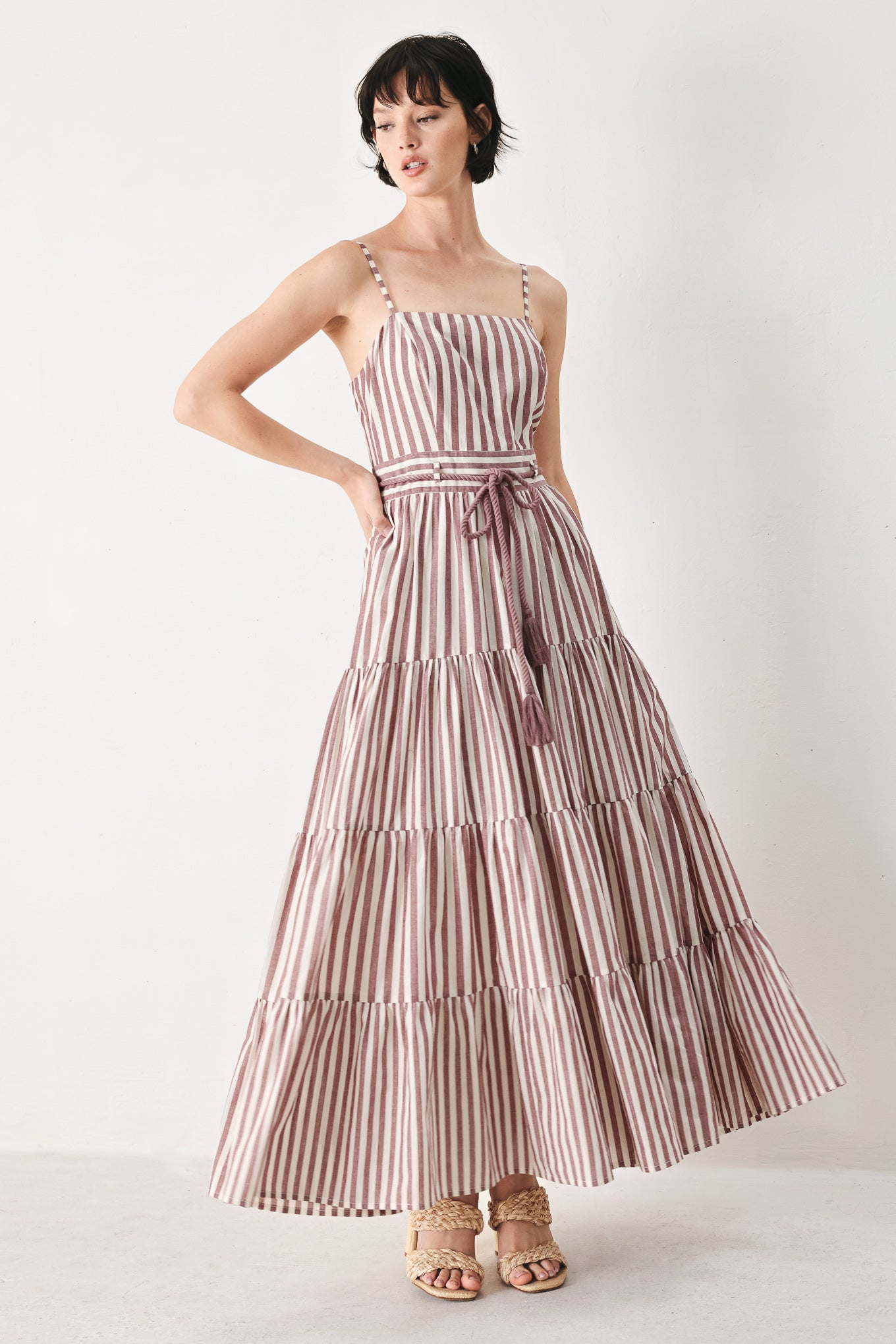 Woman wearing a burgundy striped woven ankle dress featuring straight neckline, straps, rope tie, tier skirt and back zipper closure | FREEMARKET