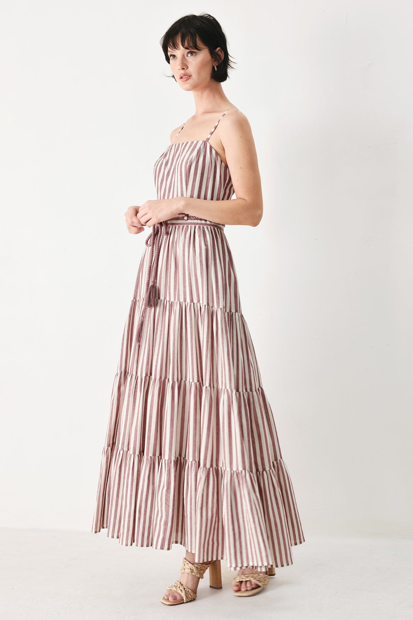 Woman wearing a burgundy striped woven ankle dress featuring straight neckline, straps, rope tie, tier skirt and back zipper closure | FREEMARKET