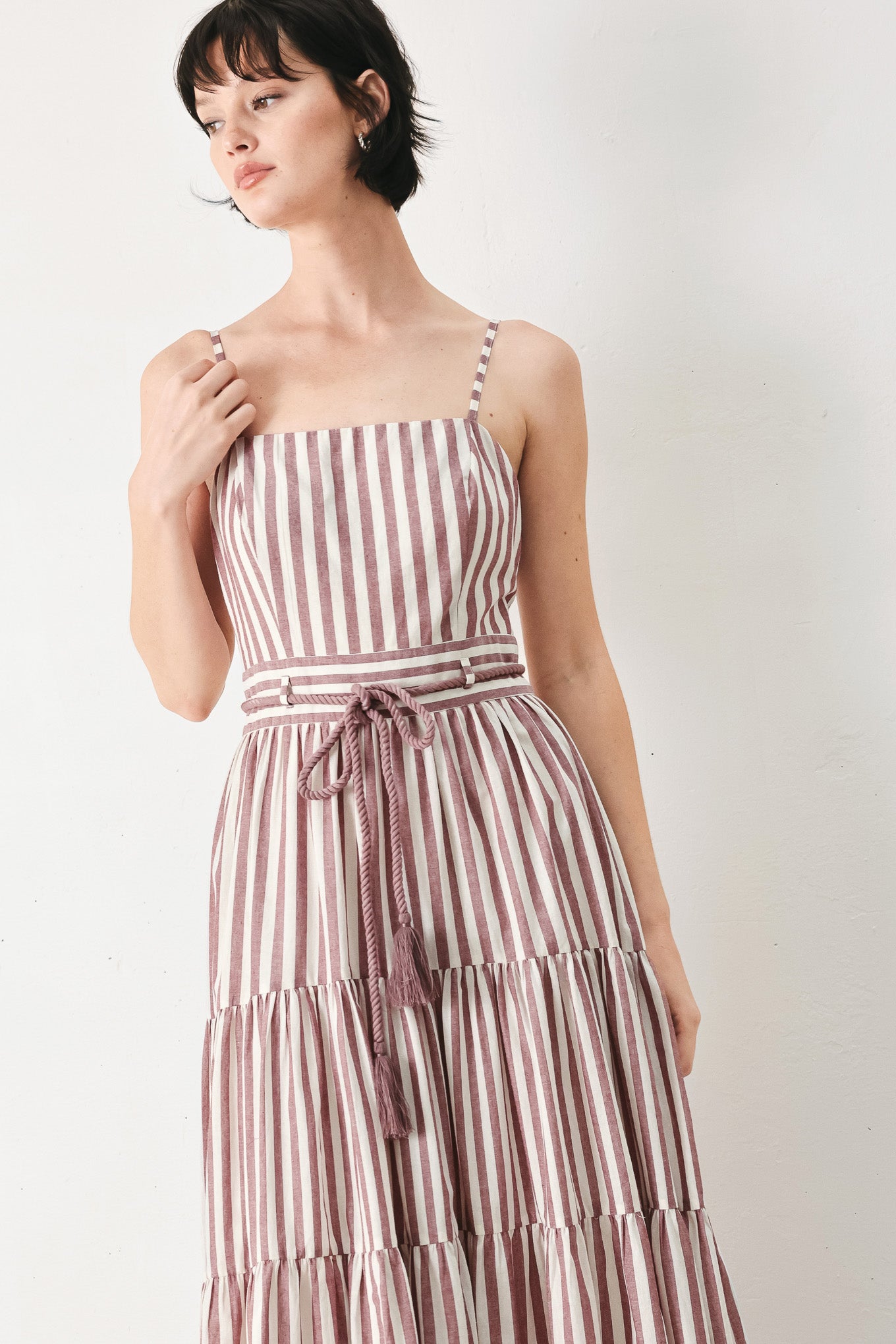 Woman wearing a burgundy striped woven ankle dress featuring straight neckline, straps, rope tie, tier skirt and back zipper closure | FREEMARKET