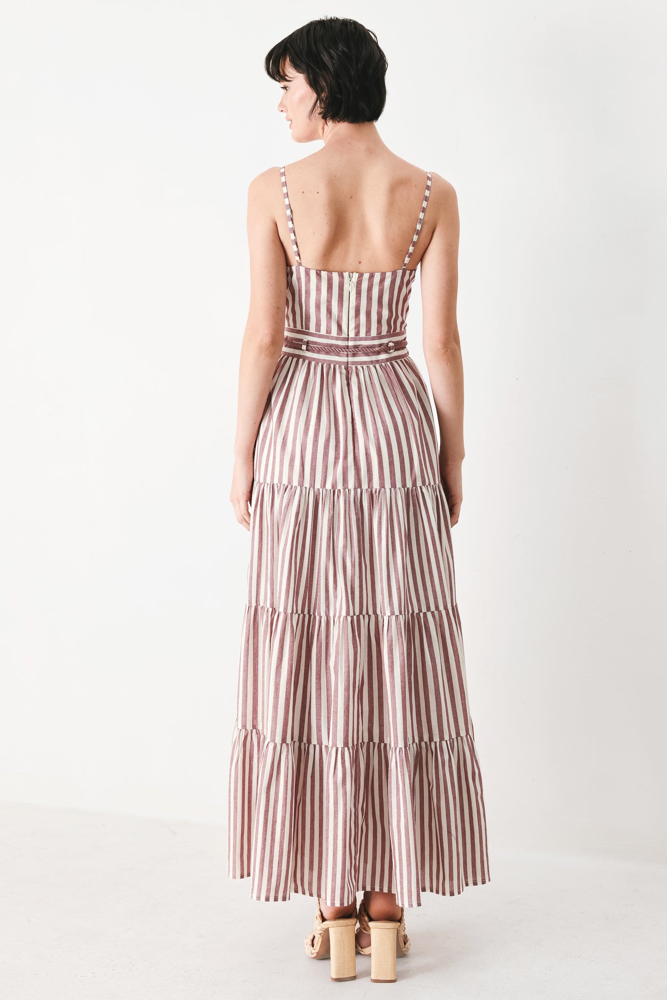 Woman wearing a burgundy striped woven ankle dress featuring straight neckline, straps, rope tie, tier skirt and back zipper closure | FREEMARKET