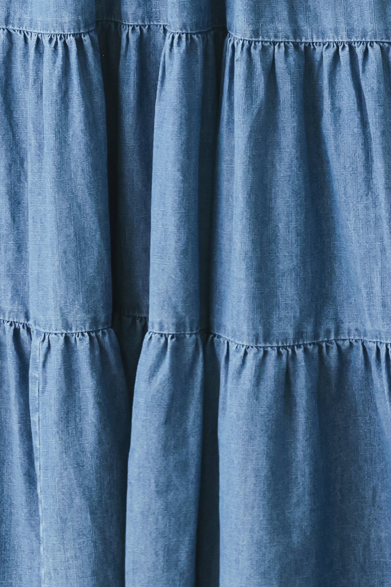 Woman wearing a blue denim midi dress featuring halter neckline, elastic waist, tier skirt, and bare back with tie | FREEMARKET