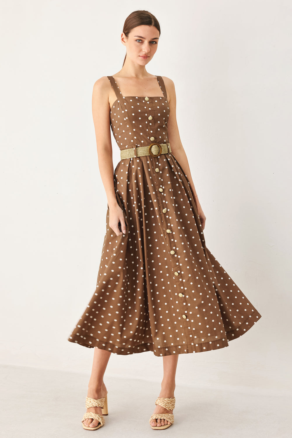 Woman wearing a brown with white polka dot midi dress featuring straight neckline, straps, button down detail, contrasting belt, full skirt and back zipper closure | FREEMARKET