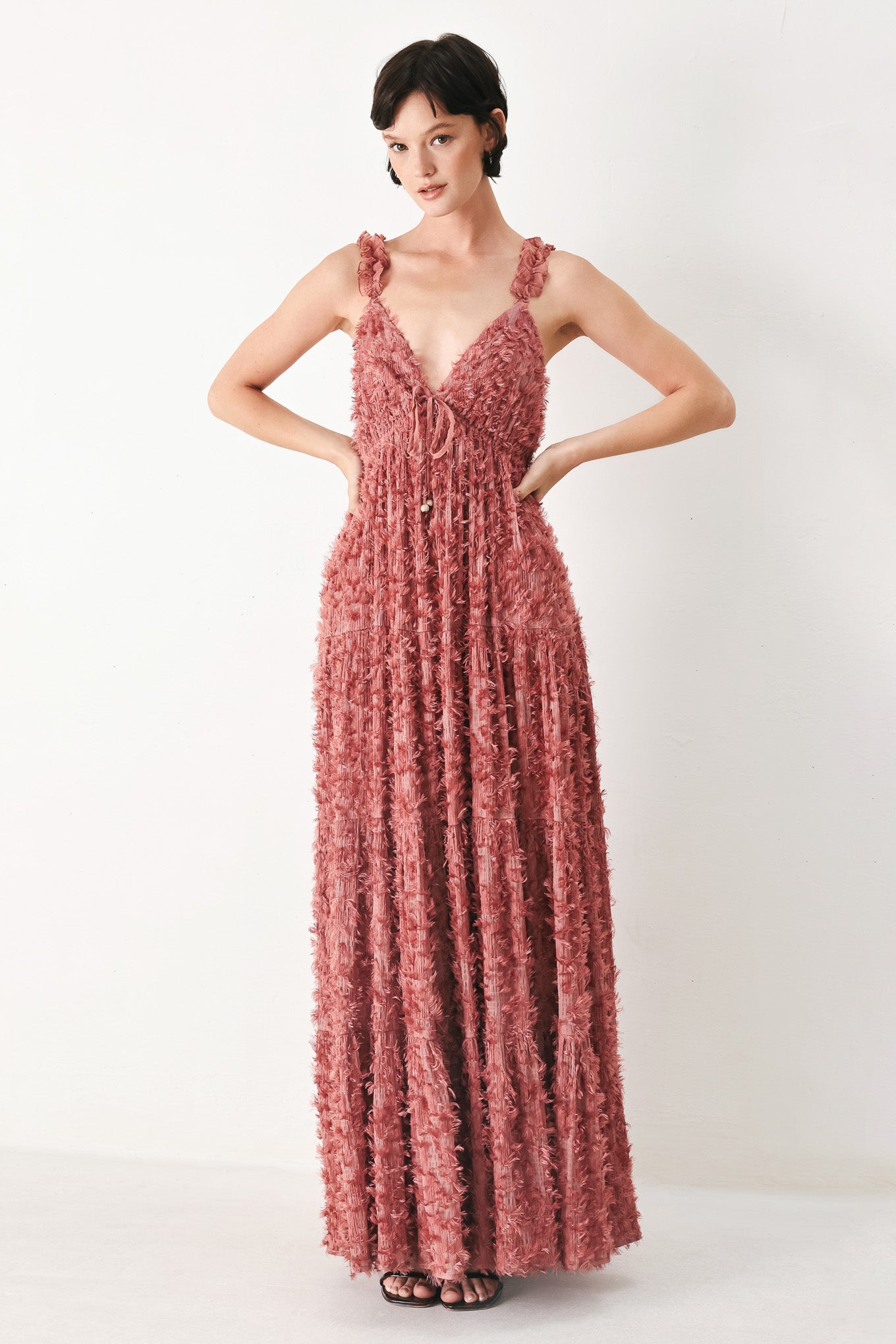Woman wearing a rose pink textured maxi dress featuring cami top, ruffled straps, front tie, empire waist and tier skirt | FREEMARKET