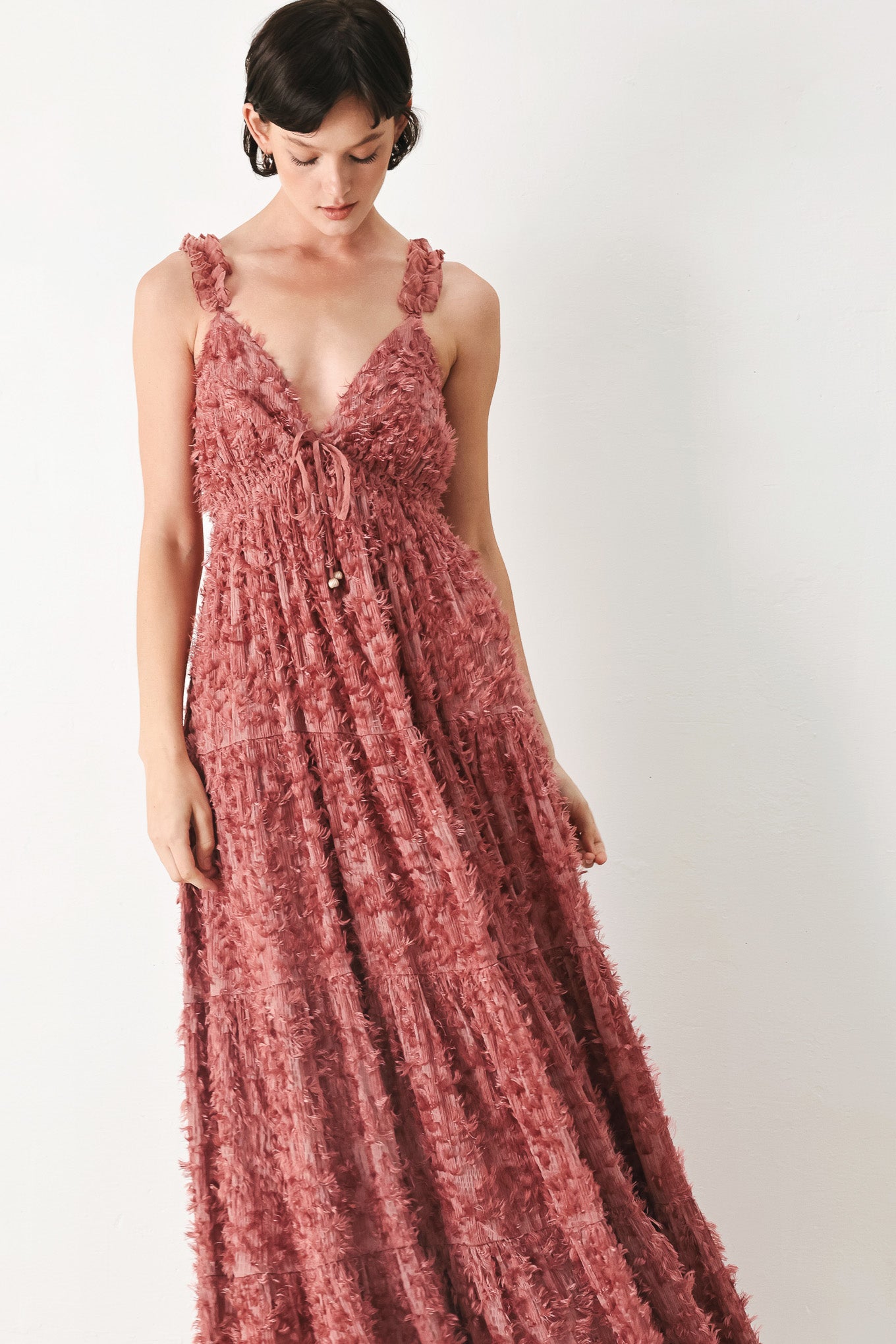 Woman wearing a rose pink textured maxi dress featuring cami top, ruffled straps, front tie, empire waist and tier skirt | FREEMARKET