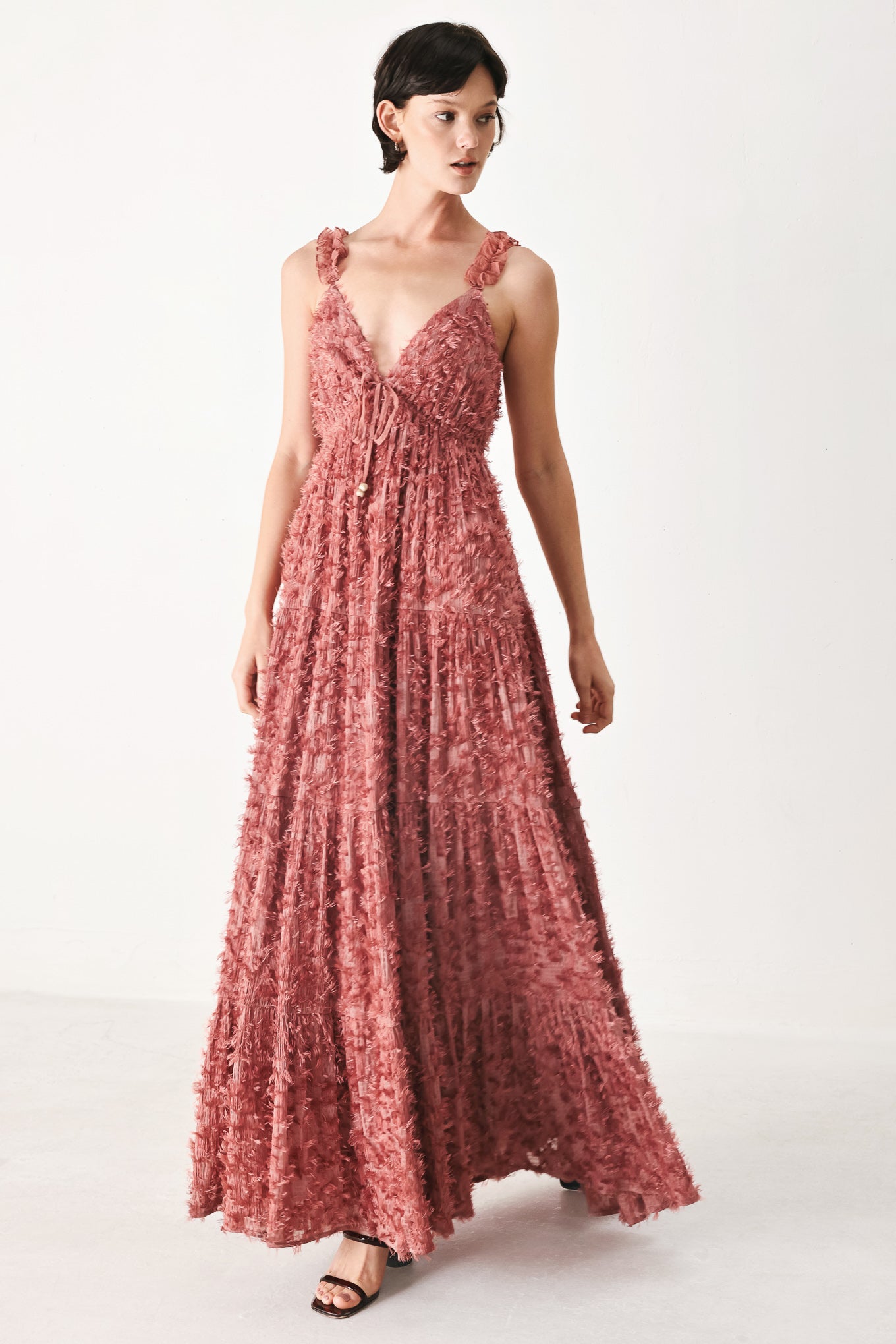 Woman wearing a rose pink textured maxi dress featuring cami top, ruffled straps, front tie, empire waist and tier skirt | FREEMARKET