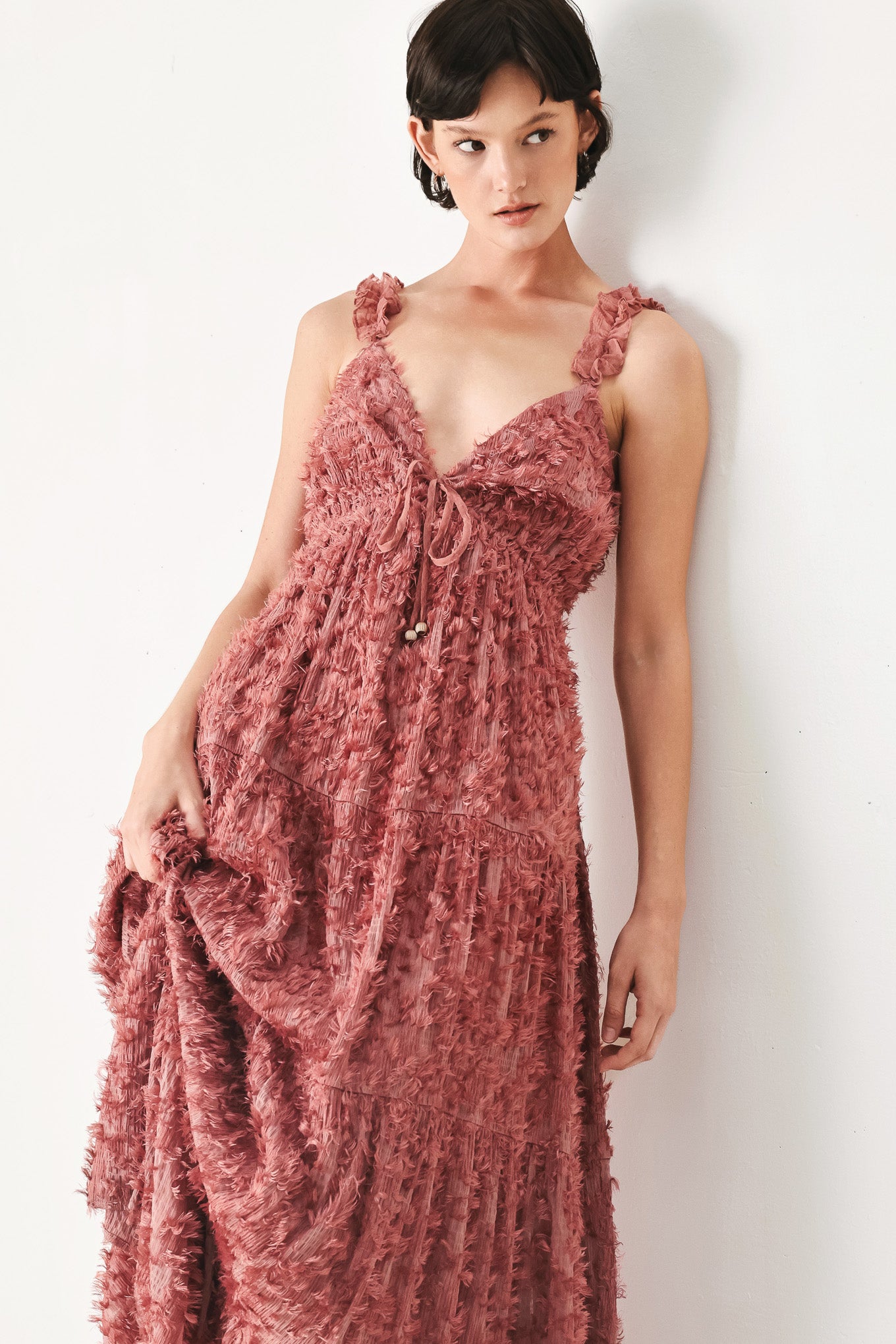 Woman wearing a rose pink textured maxi dress featuring cami top, ruffled straps, front tie, empire waist and tier skirt | FREEMARKET