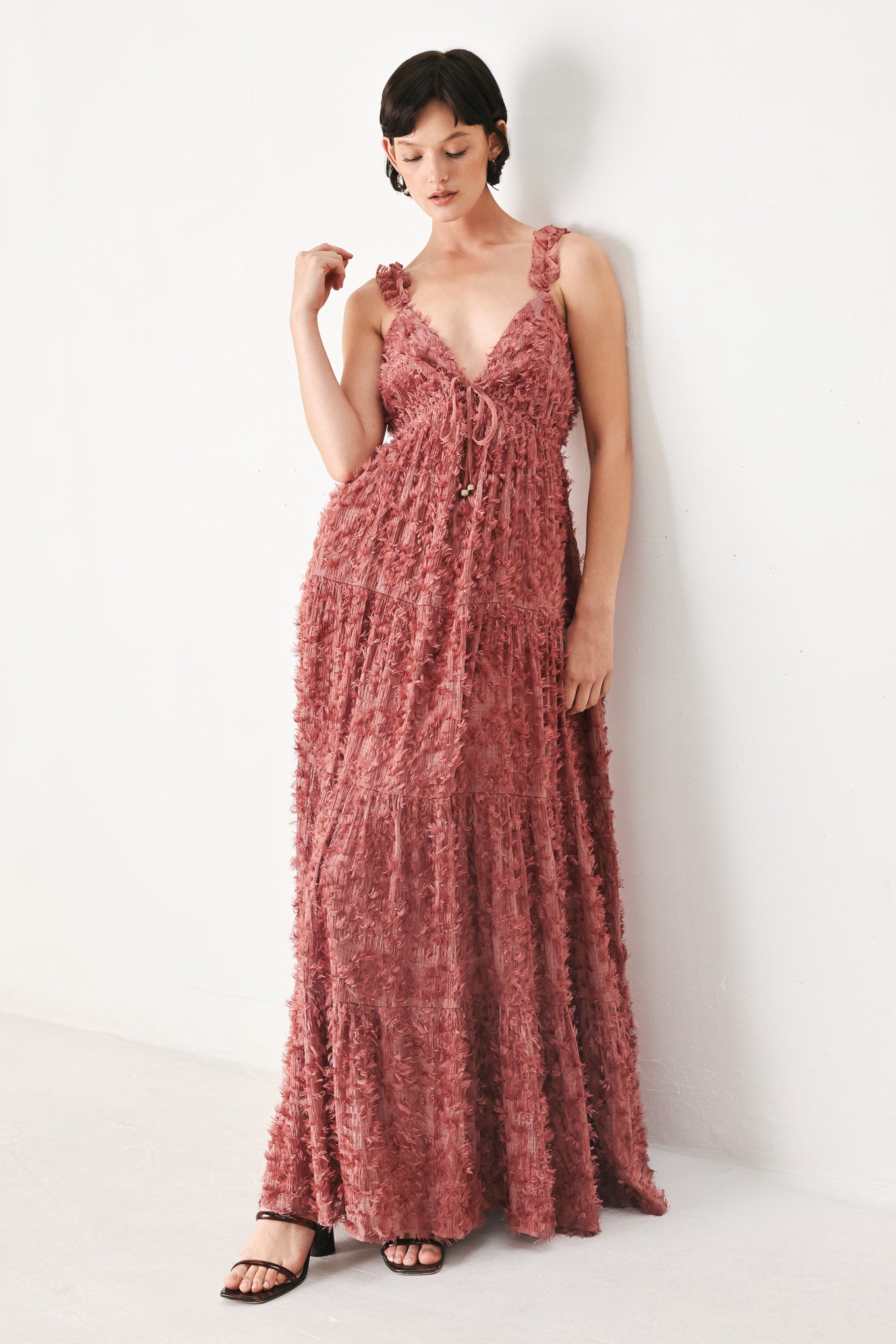 Woman wearing a rose pink textured maxi dress featuring cami top, ruffled straps, front tie, empire waist and tier skirt | FREEMARKET