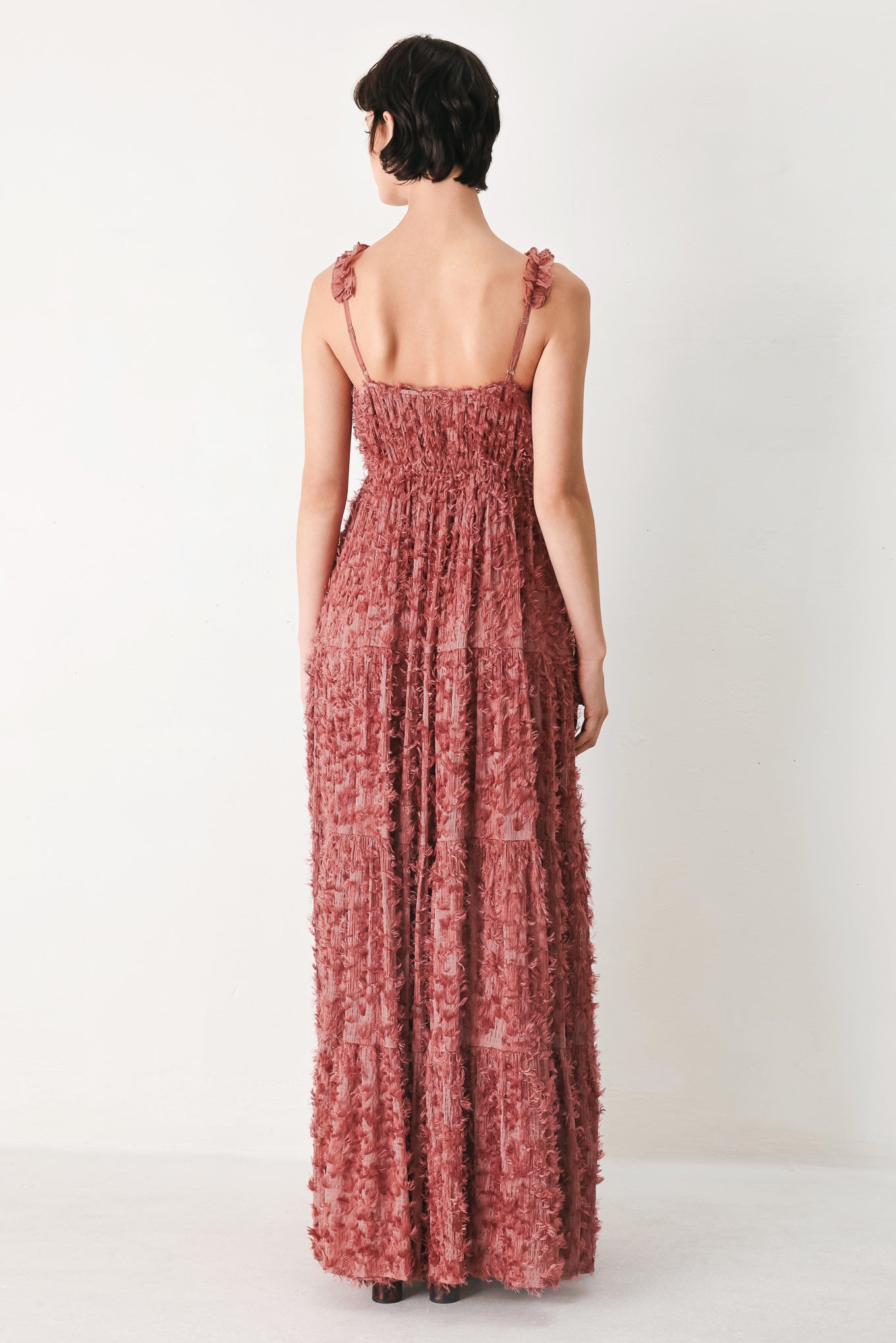 Woman wearing a rose pink textured maxi dress featuring cami top, ruffled straps, front tie, empire waist and tier skirt | FREEMARKET