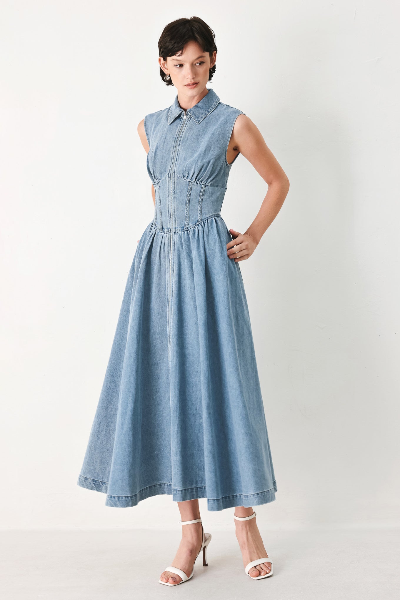 Woman wearing a denim midi dress with collar, sleeveless, front zipper closure, corset waist and full skirt | FREEMARKET