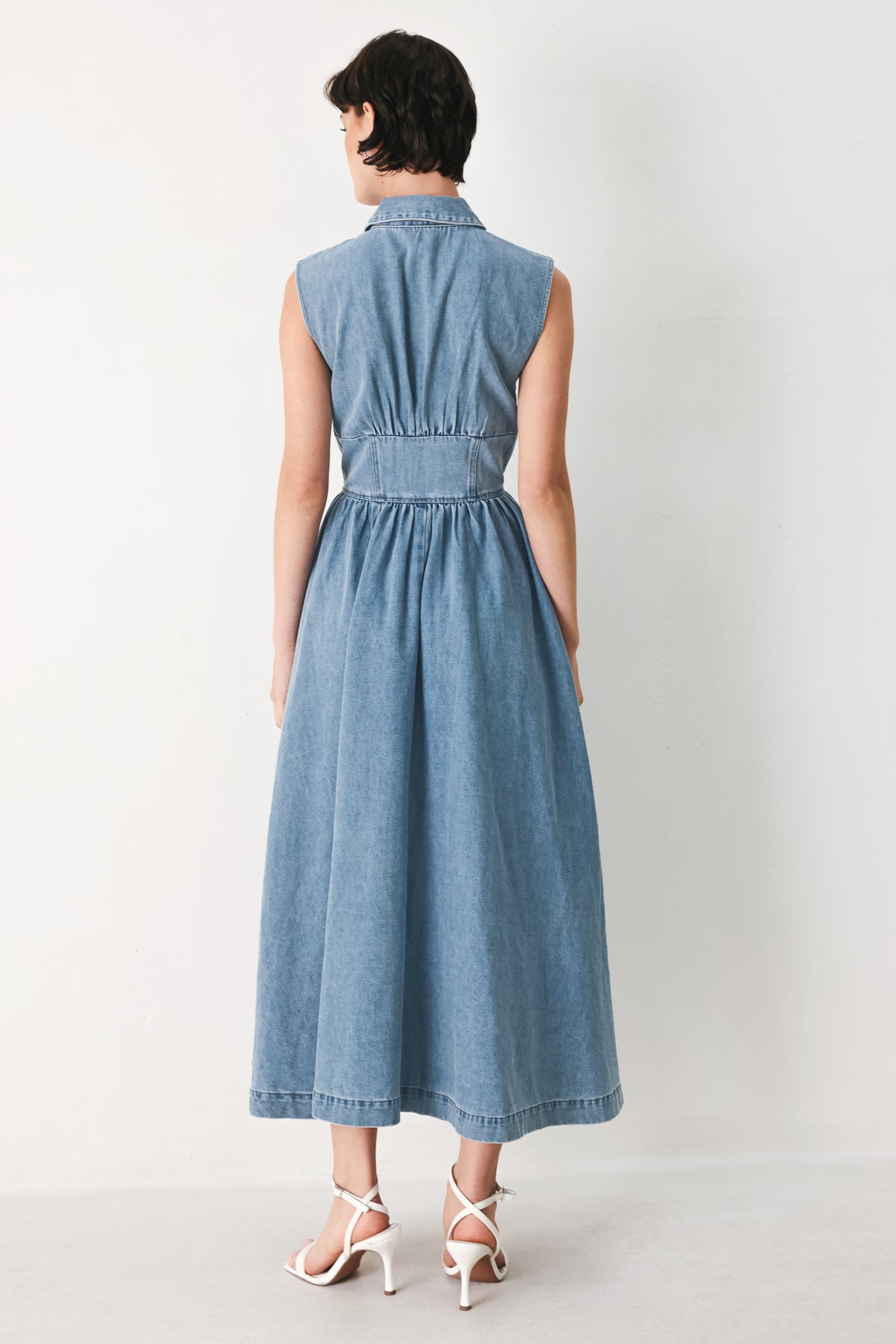 Woman wearing a denim midi dress with collar, sleeveless, front zipper closure, corset waist and full skirt | FREEMARKET