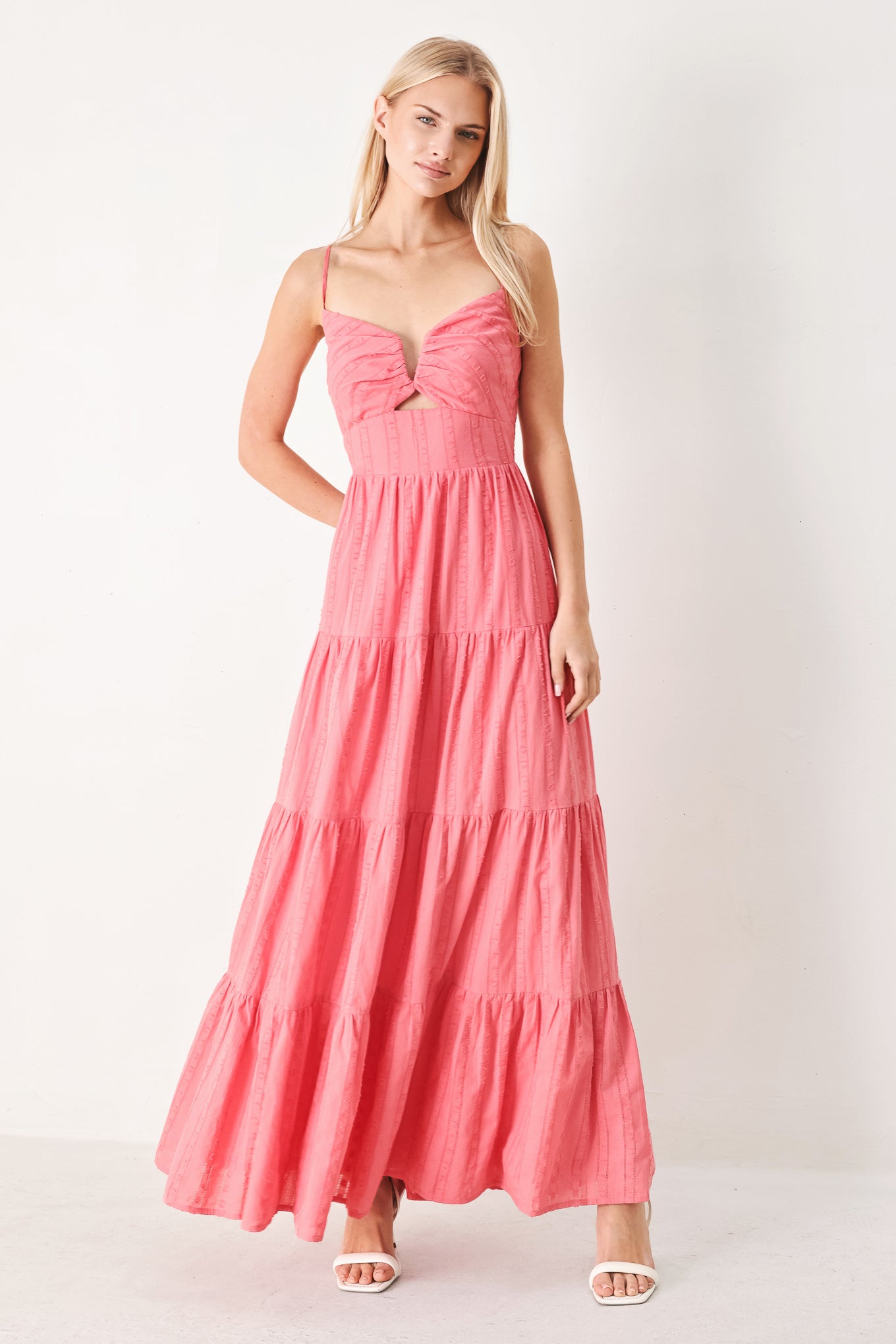 Woman wearing a pink tiered maxi dress with front cut out, self sash, tier skirt and smocked back bodice | FREEMARKET