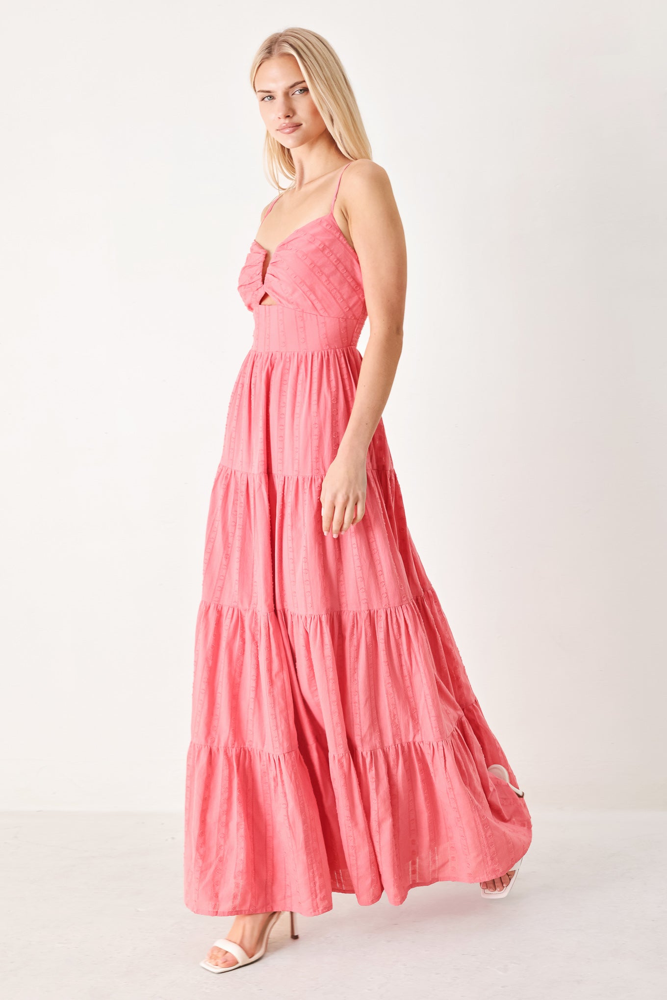 Woman wearing a pink tiered maxi dress with front cut out, self sash, tier skirt and smocked back bodice | FREEMARKET
