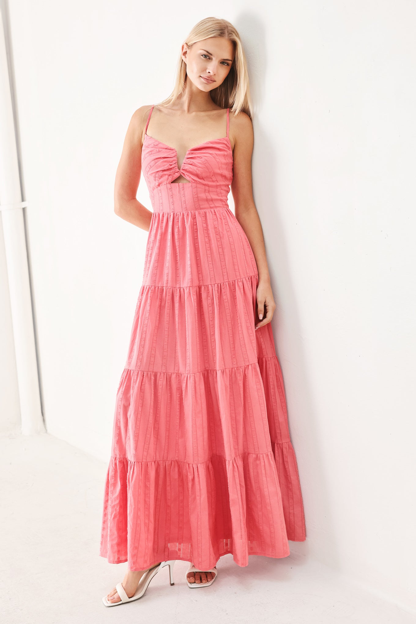 Woman wearing a pink tiered maxi dress with front cut out, self sash, tier skirt and smocked back bodice | FREEMARKET