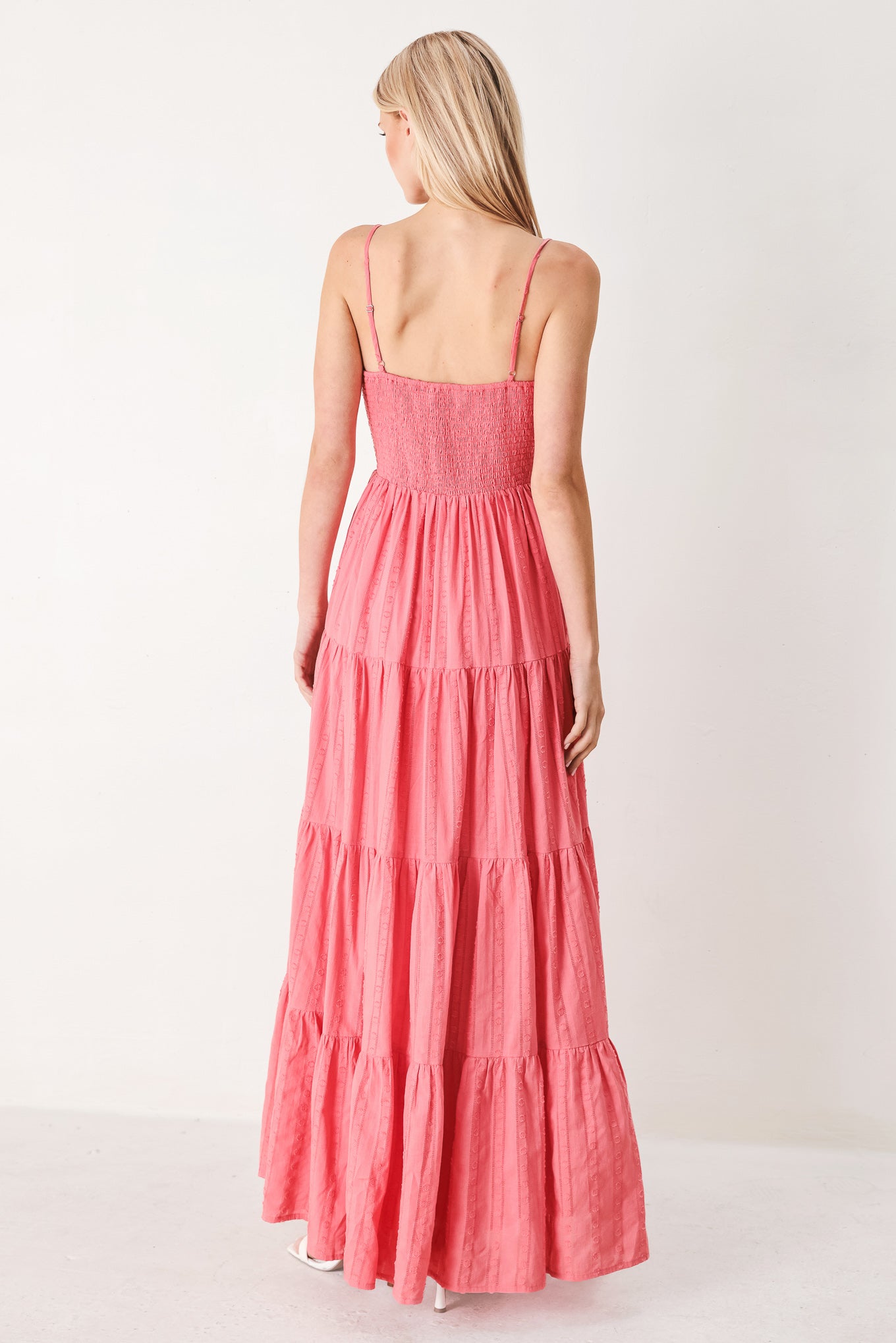 Woman wearing a pink tiered maxi dress with front cut out, self sash, tier skirt and smocked back bodice | FREEMARKET