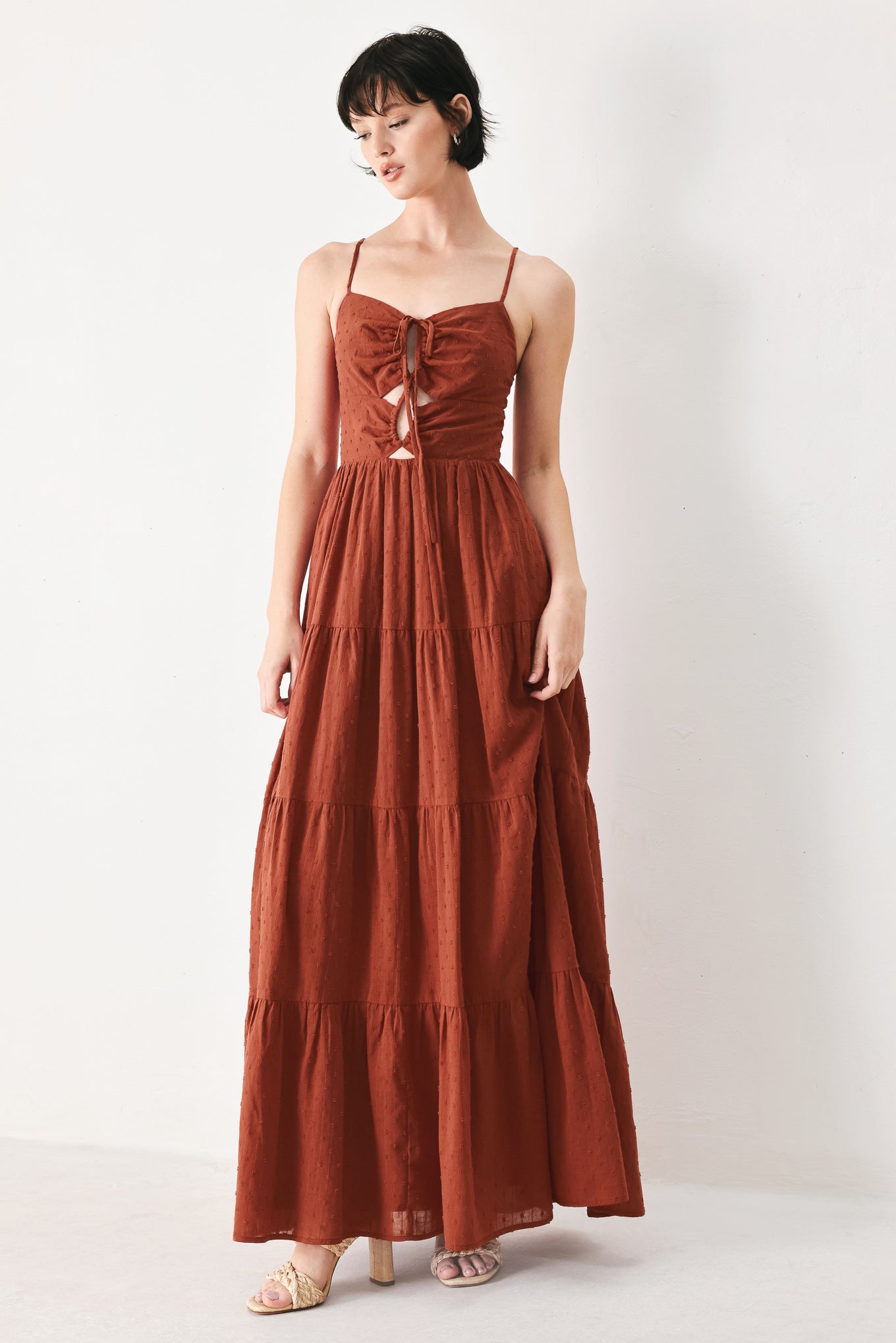 Woman wearing a rust solid textured woven maxi dress featuring cami top with front center cut out, straps, tier skirt and back zipper closure | FREEMARKET