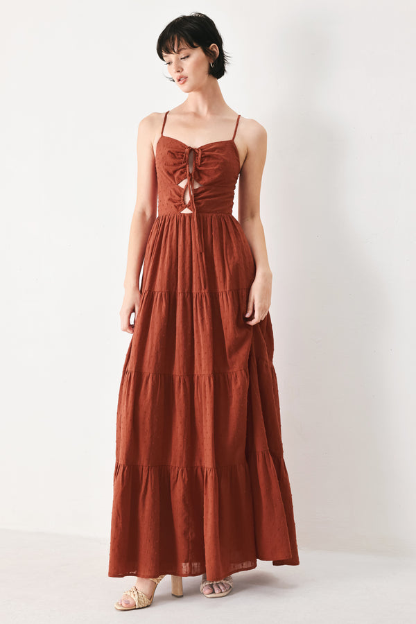 Woman wearing a rust solid textured woven maxi dress featuring cami top with front center cut out, straps, tier skirt and back zipper closure | FREEMARKET