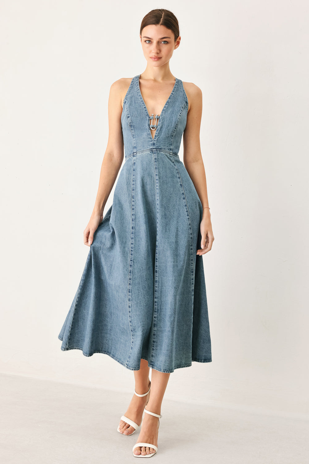 Woman wearing a blue denim midi dress featuring V neckline with hardware, circle skirt, bare back with cross strap and zipper closure | FREEMARKET