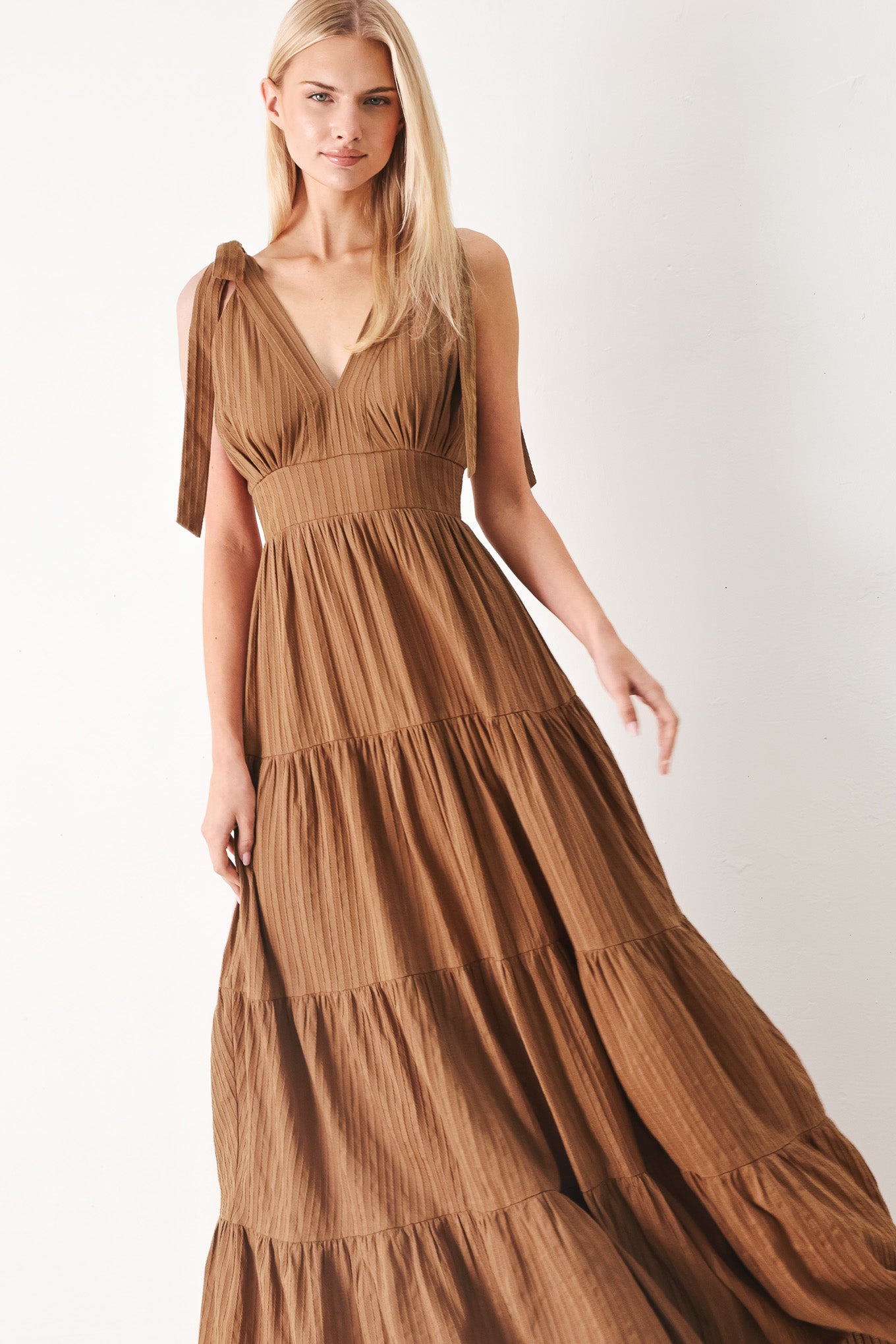 Woman wearing a brown tiered maxi dress featuring V neckline, shoulder ties, tier skirt and smocked back waistband | FREEMARKET