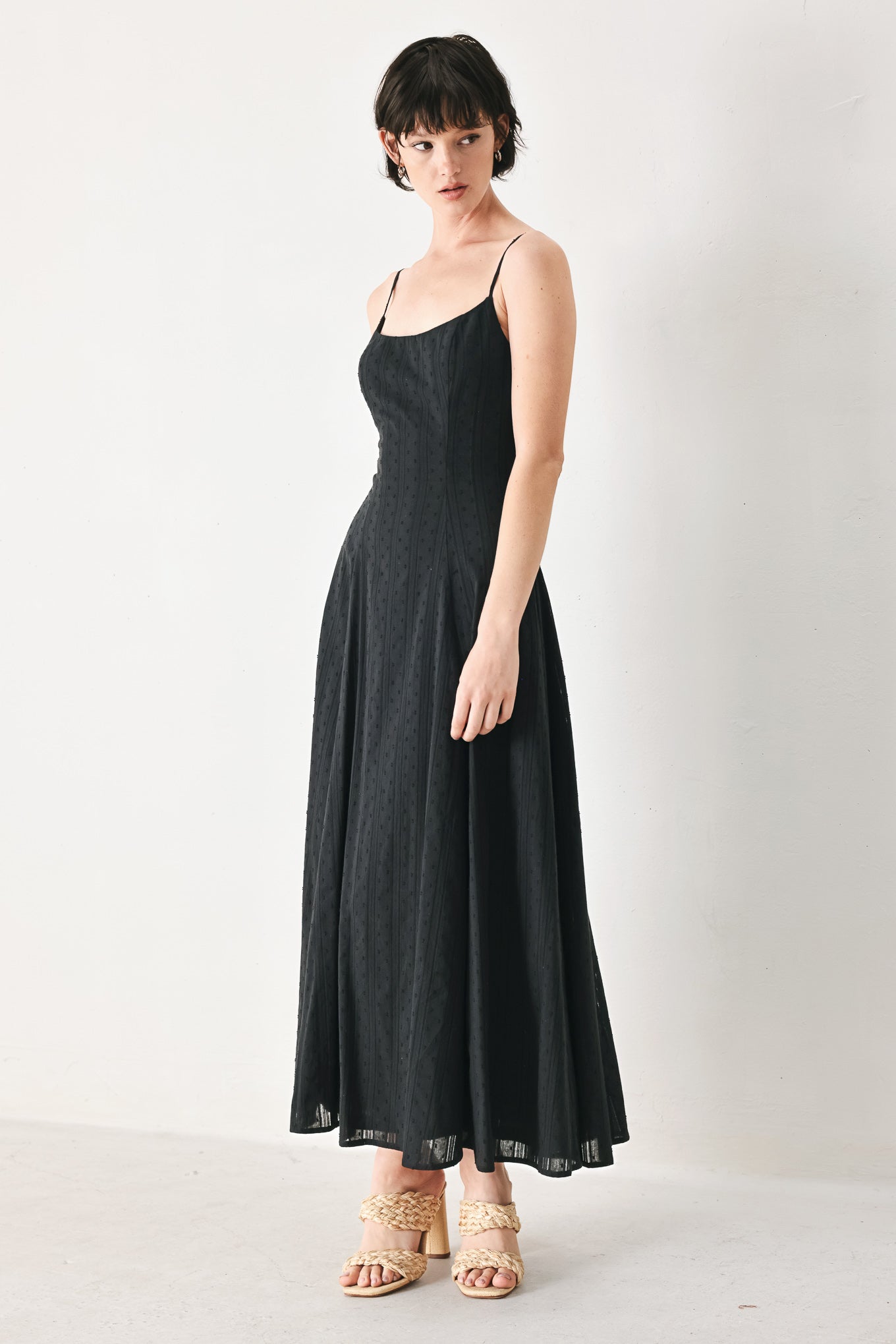 Woman wearing a black midi dress with straps, circle skirt and back zipper closure | FREEMARKET