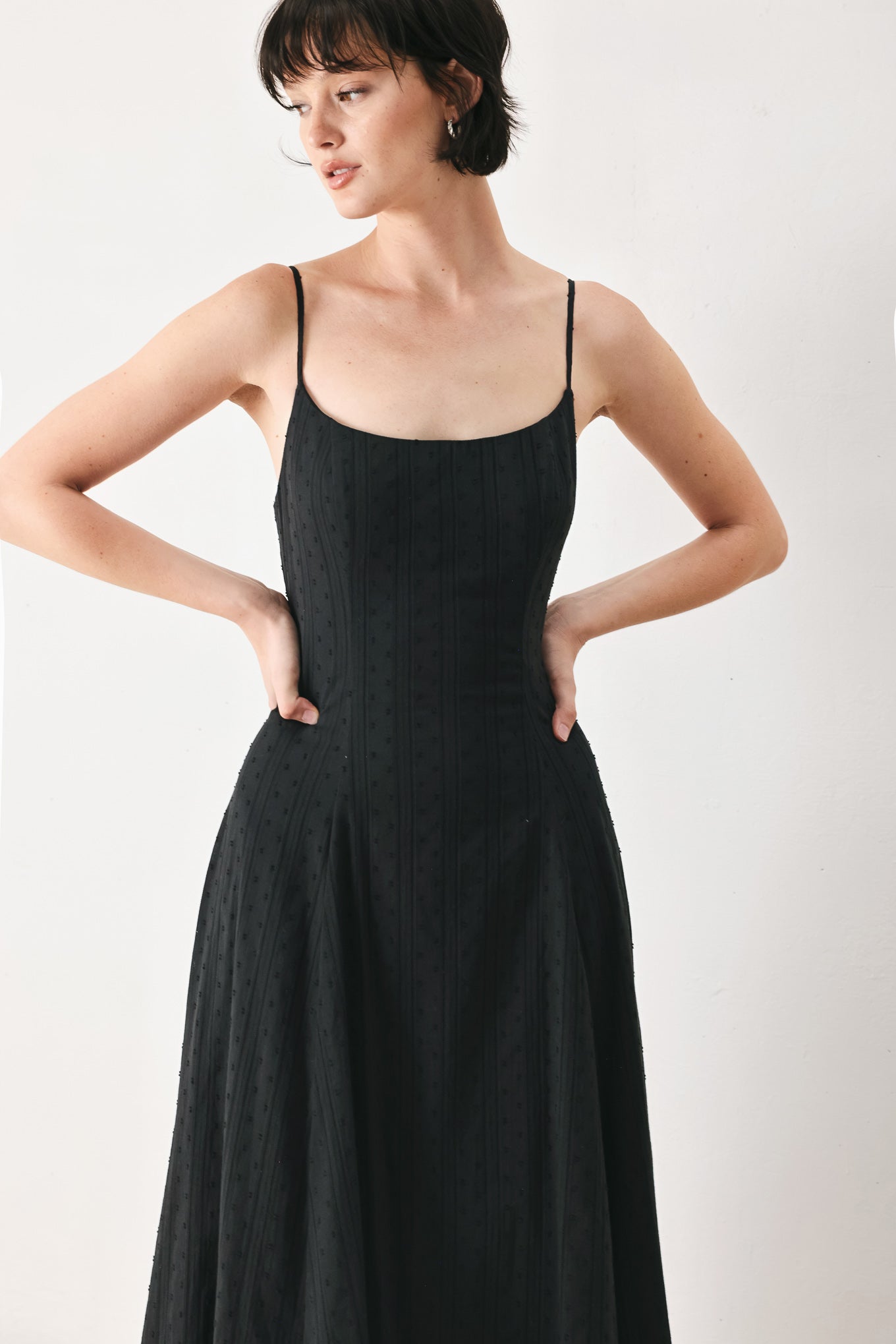 Woman wearing a black midi dress with straps, circle skirt and back zipper closure | FREEMARKET