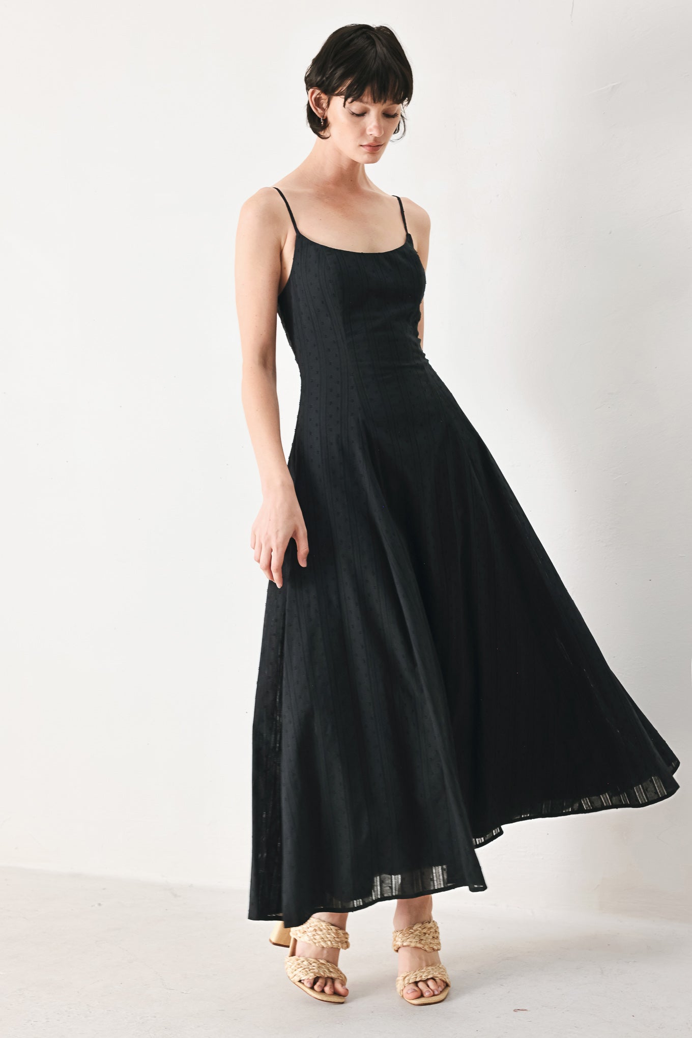 Woman wearing a black midi dress with straps, circle skirt and back zipper closure | FREEMARKET