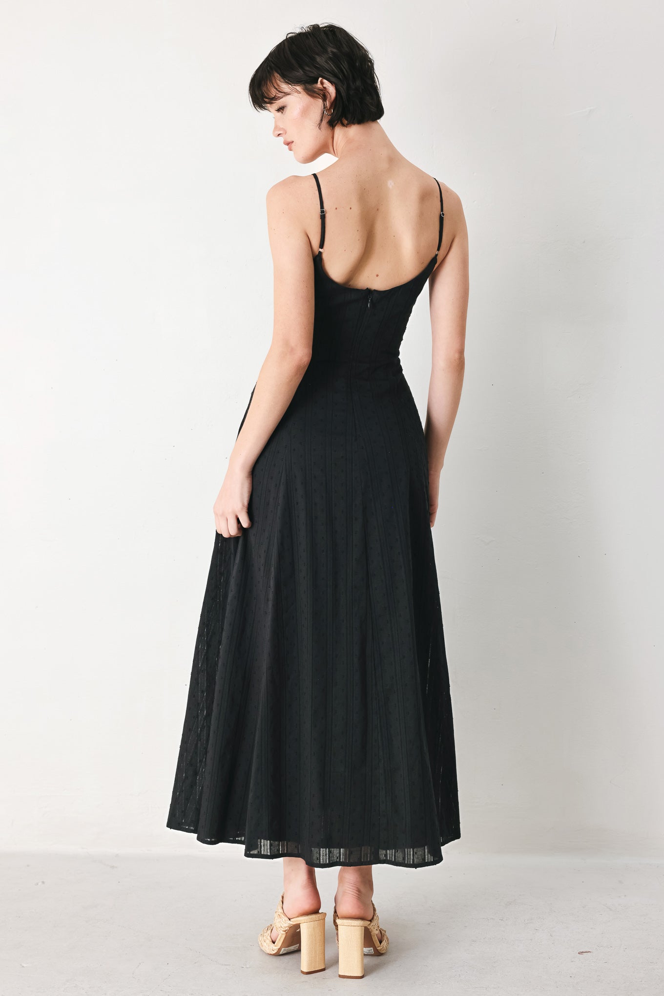 Woman wearing a black midi dress with straps, circle skirt and back zipper closure | FREEMARKET