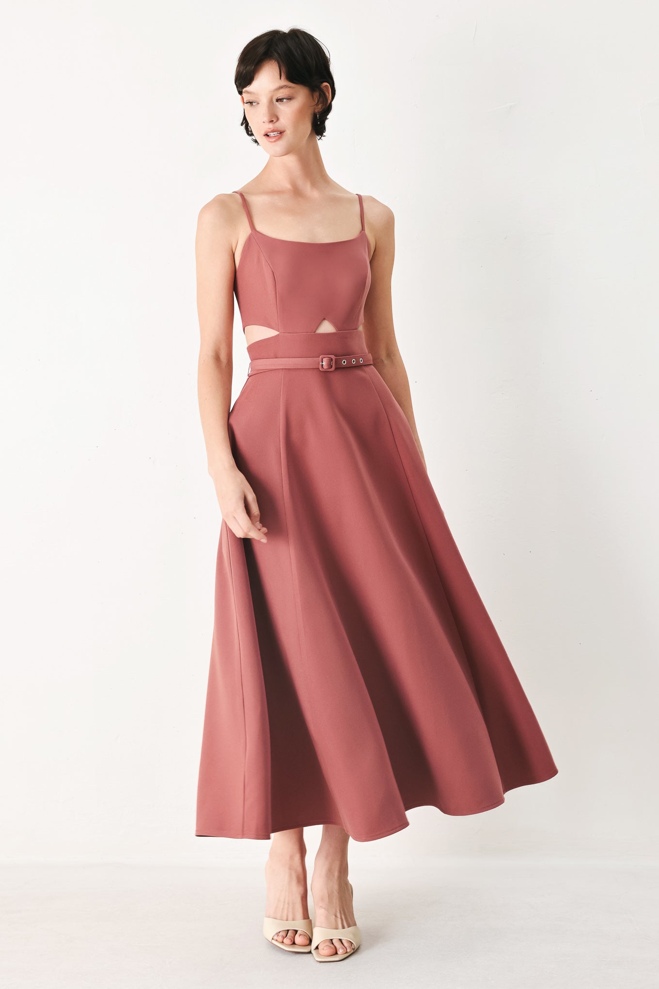 Woman wearing a rose pink midi dress with cut-out design featuring cam top, cut out at waistline, self belt, circle skirt and back zipper closure | FREEMARKET