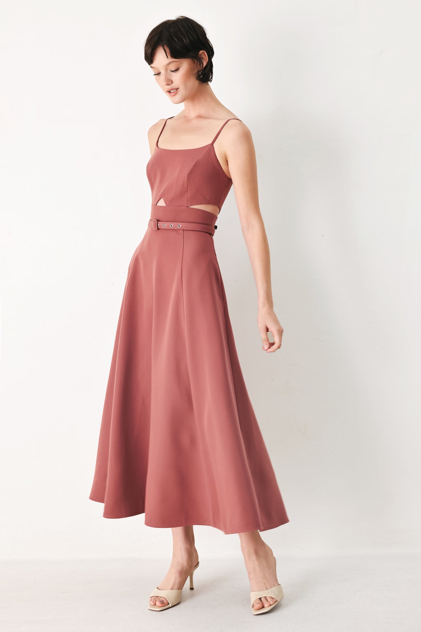 Woman wearing a rose pink midi dress with cut-out design featuring cam top, cut out at waistline, self belt, circle skirt and back zipper closure | FREEMARKET