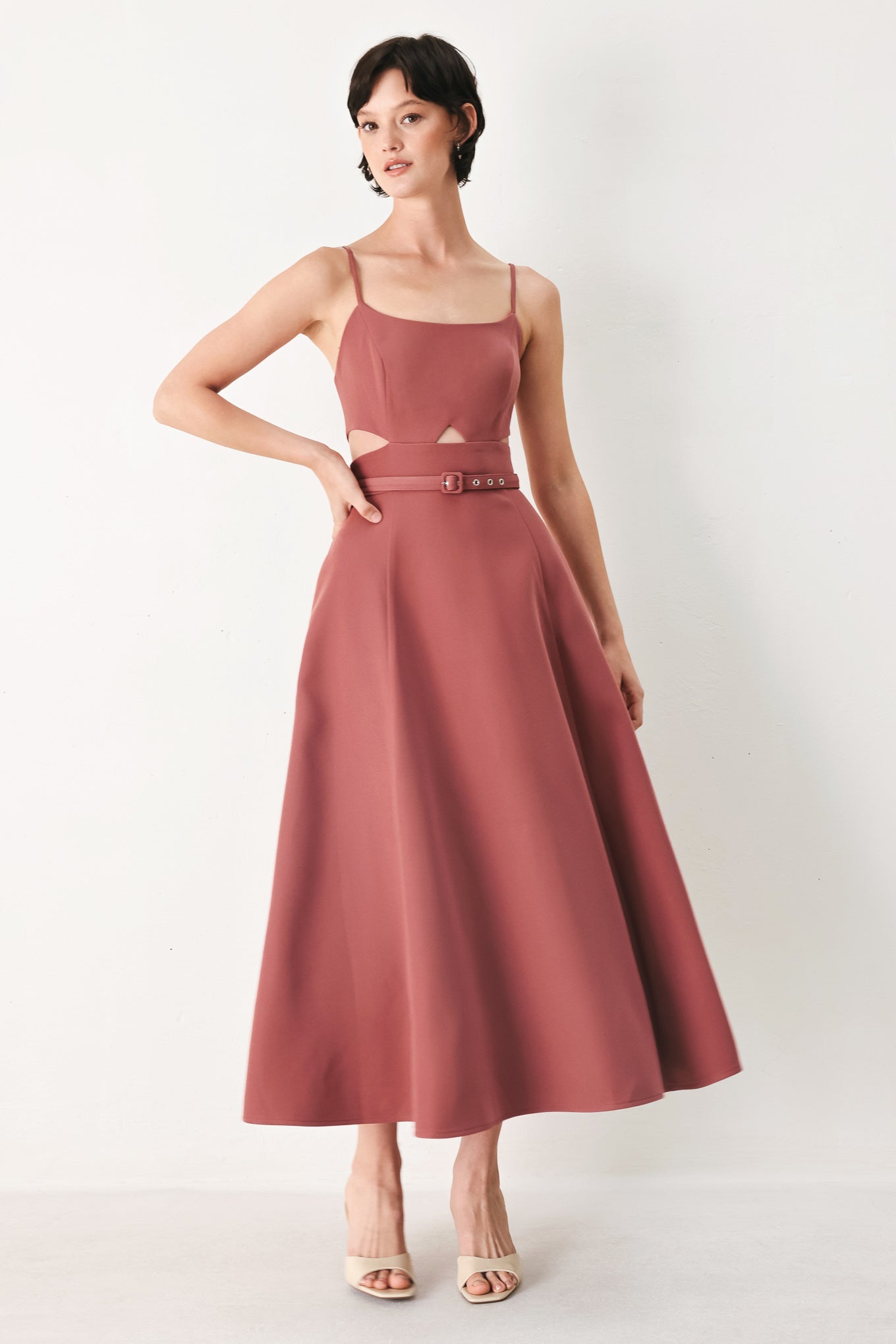 Woman wearing a rose pink midi dress with cut-out design featuring cam top, cut out at waistline, self belt, circle skirt and back zipper closure | FREEMARKET