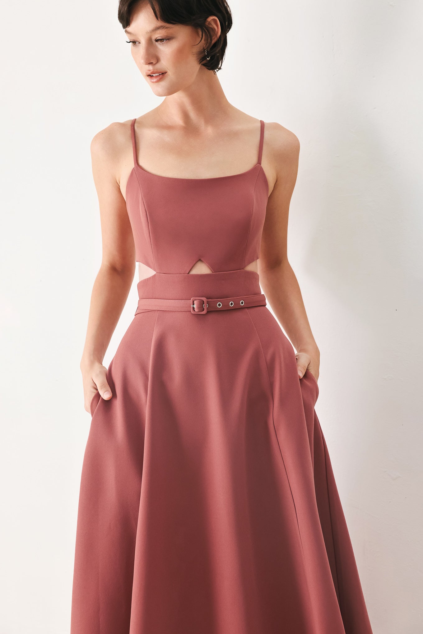 Woman wearing a rose pink midi dress with cut-out design featuring cam top, cut out at waistline, self belt, circle skirt and back zipper closure | FREEMARKET